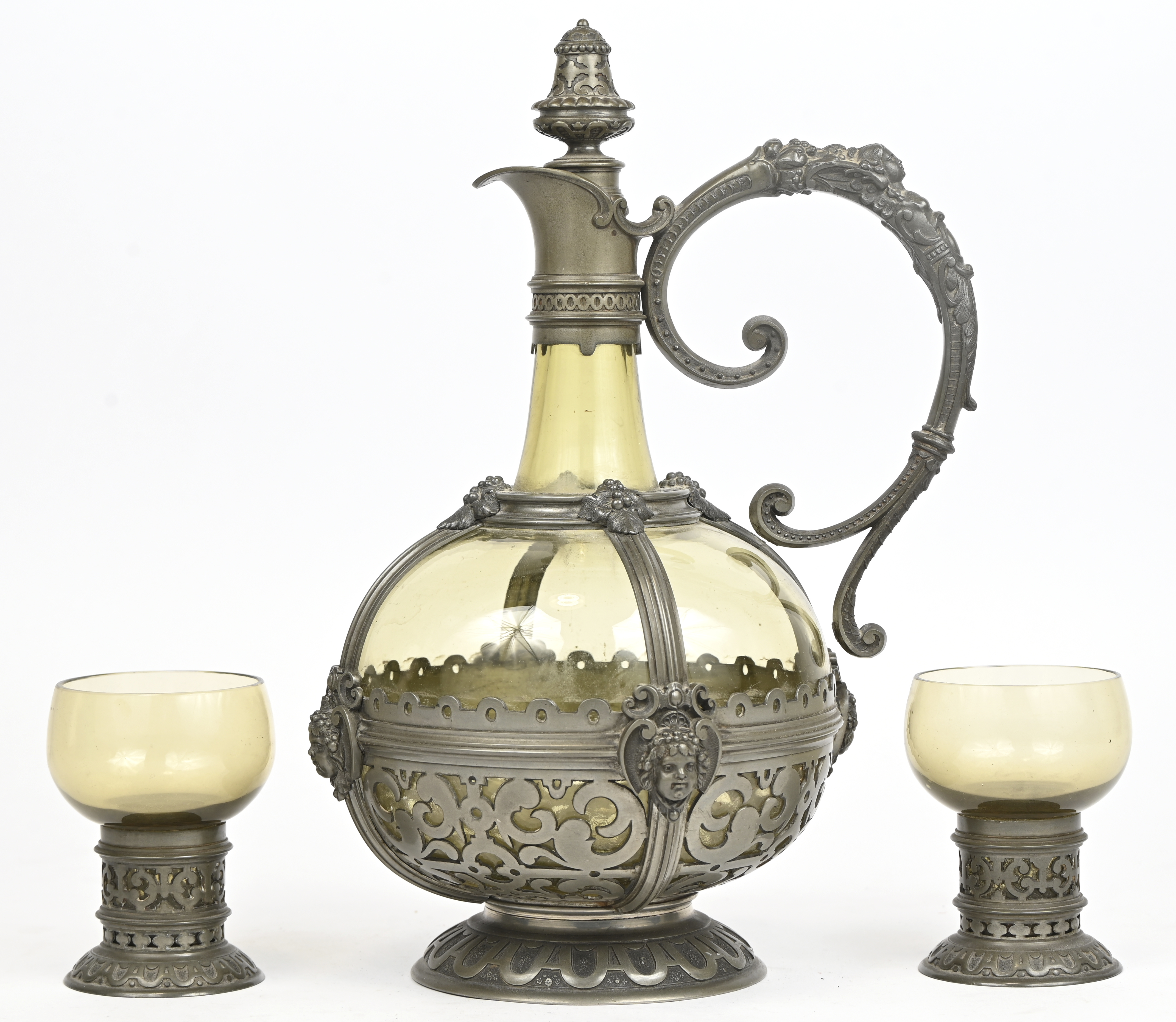 Een karaf met 2 glazen, tin en glas, in Neo Renaissance stijl Een karaf met 2 glazen, tin en glas, in Neo Renaissance stijl.