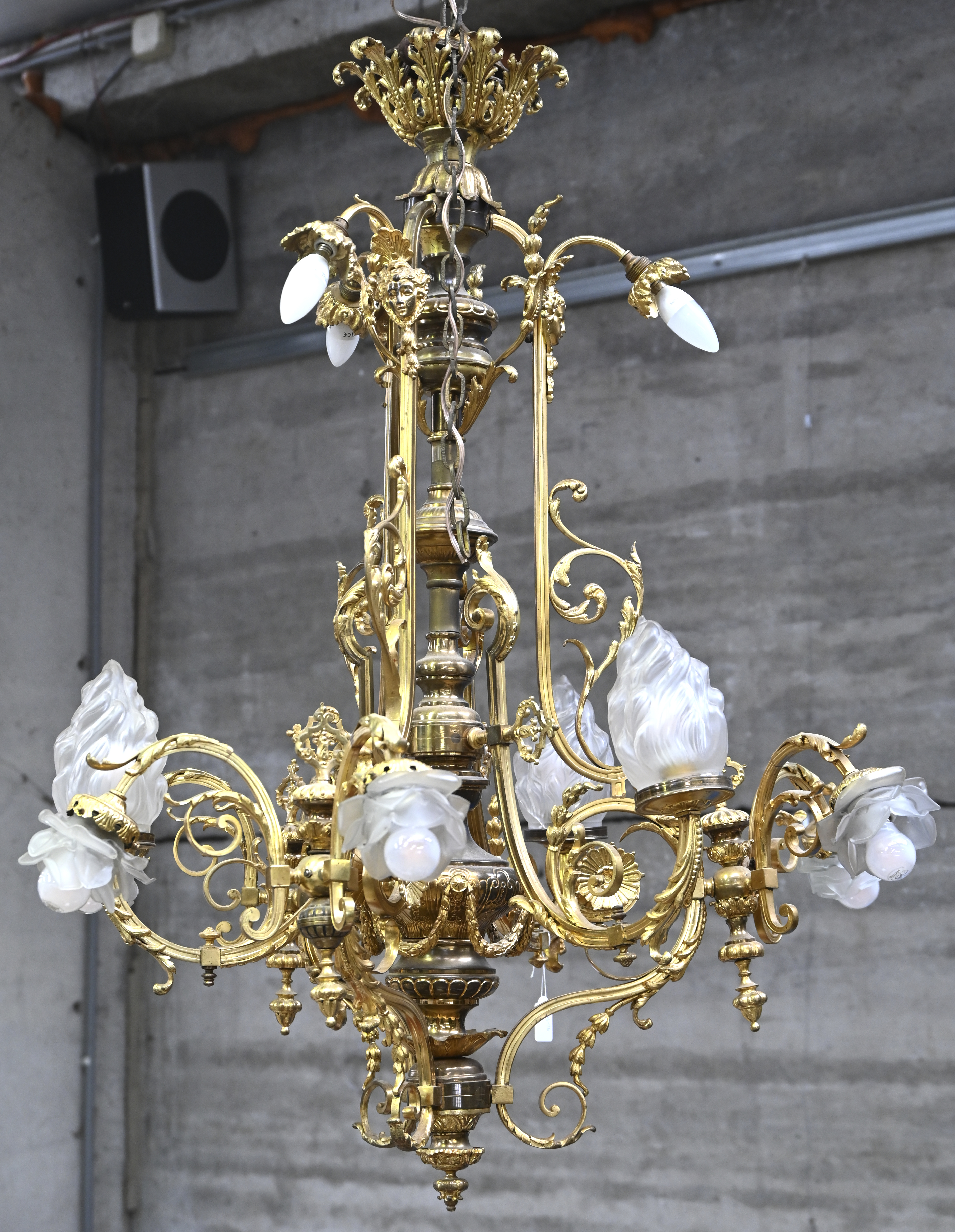 Een grote verguld bronzen luchter met glazen vlam- alsook bloemvormige blakers, waarvan met schade Een grote verguld bronzen luchter met glazen vlam- alsook bloemvormige blakers, waarvan met schade.