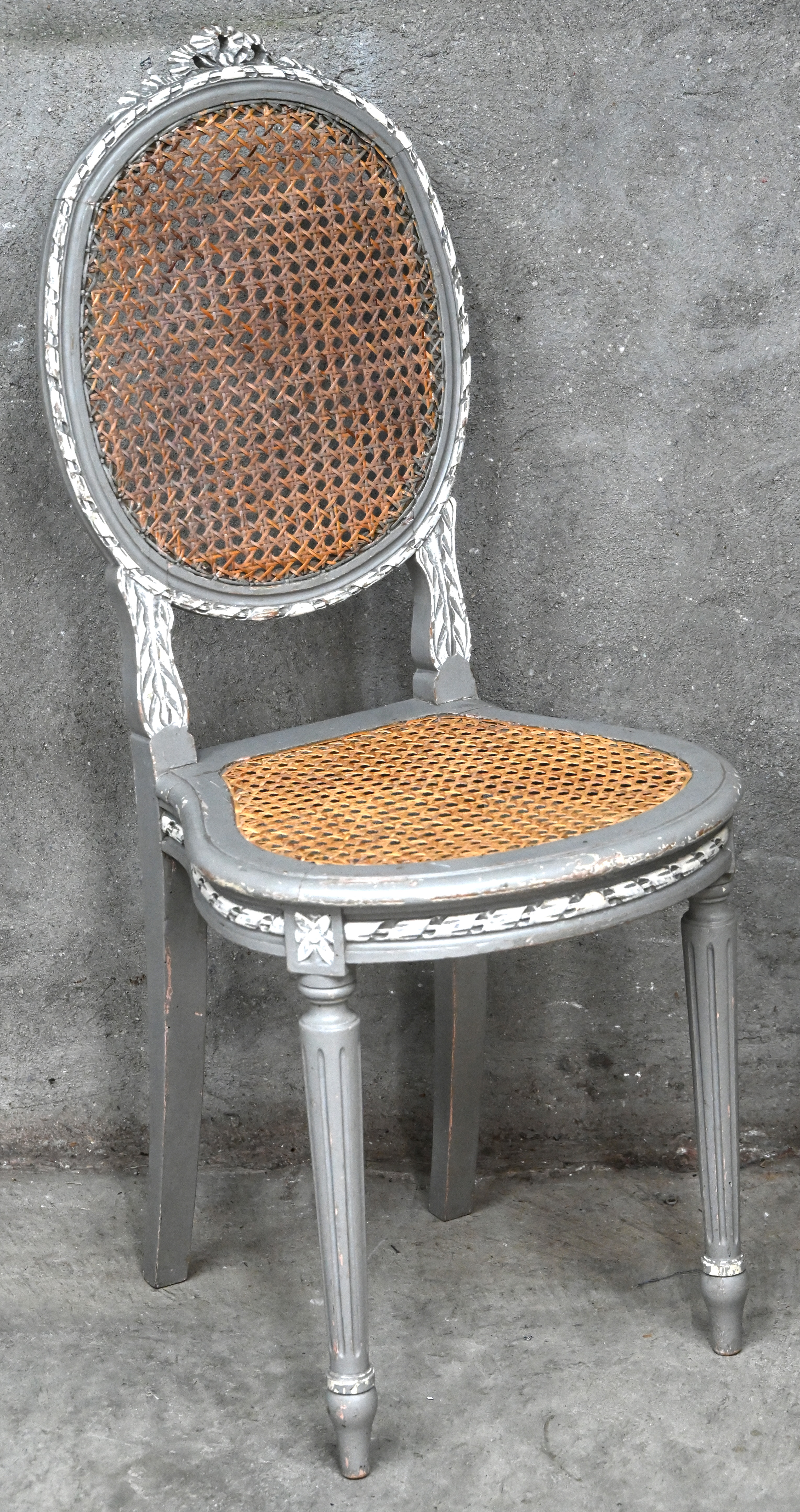 Een medaillonstoel met cannage zit en rug. Grijs met witte accenten, met mooie ouderdomspatina Een medaillonstoel met cannage zit en rug. Grijs met witte accenten, met mooie ouderdomspatina.