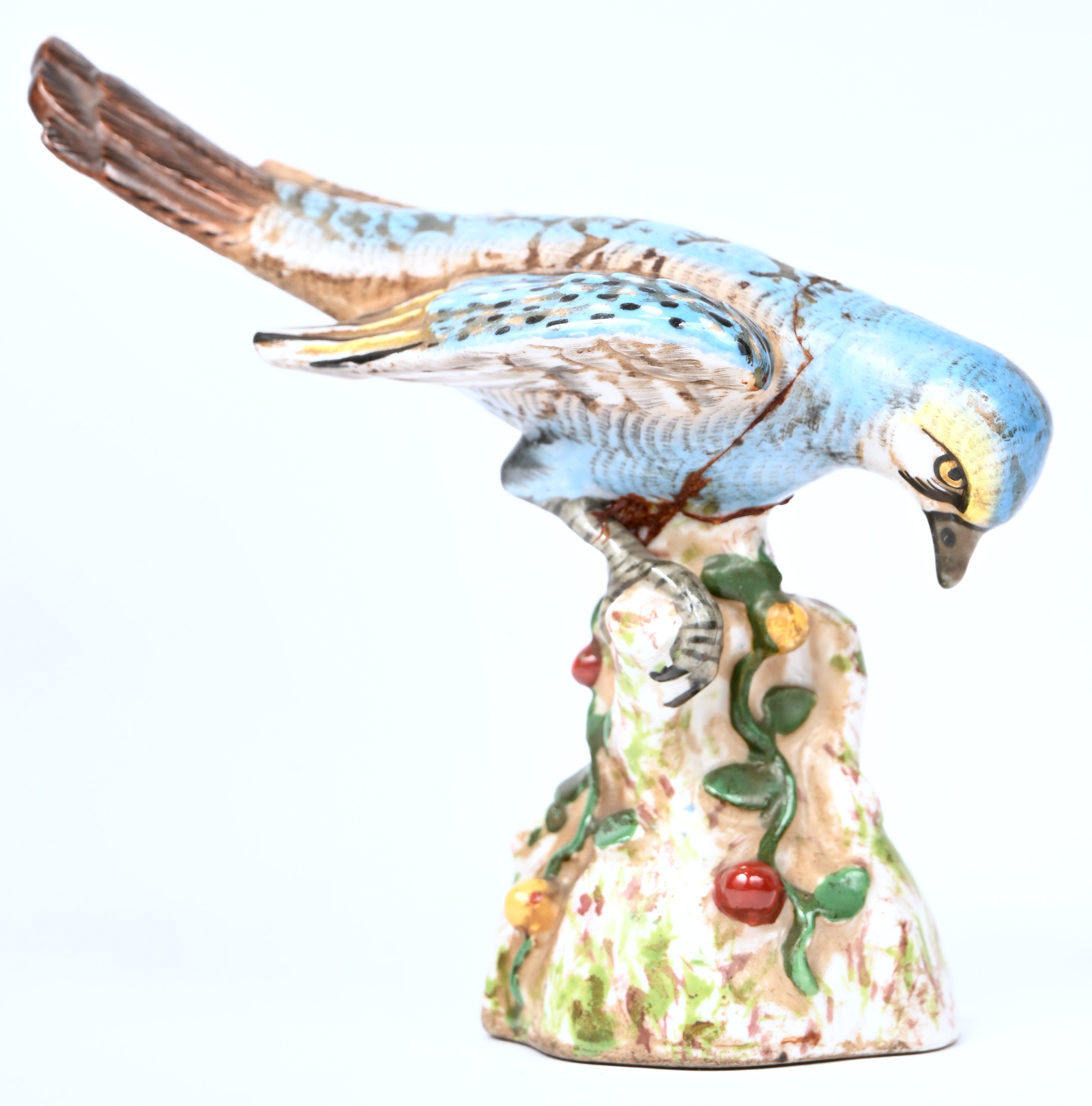 Een porseleinen beeldje van een blauwe parkiet. Gemerkt met gekruiste pijlen. Meermaals gelijmd Een porseleinen beeldje van een blauwe parkiet. Gemerkt met gekruiste pijlen. Meermaals gelijmd.