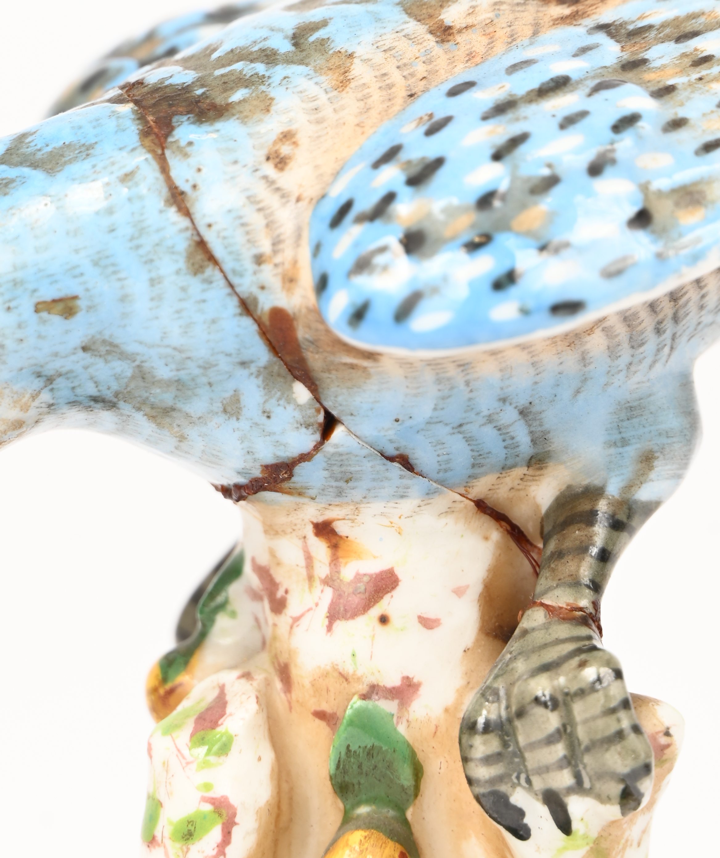 Een porseleinen beeldje van een blauwe parkiet. Gemerkt met gekruiste pijlen. Meermaals gelijmd Een porseleinen beeldje van een blauwe parkiet. Gemerkt met gekruiste pijlen. Meermaals gelijmd.