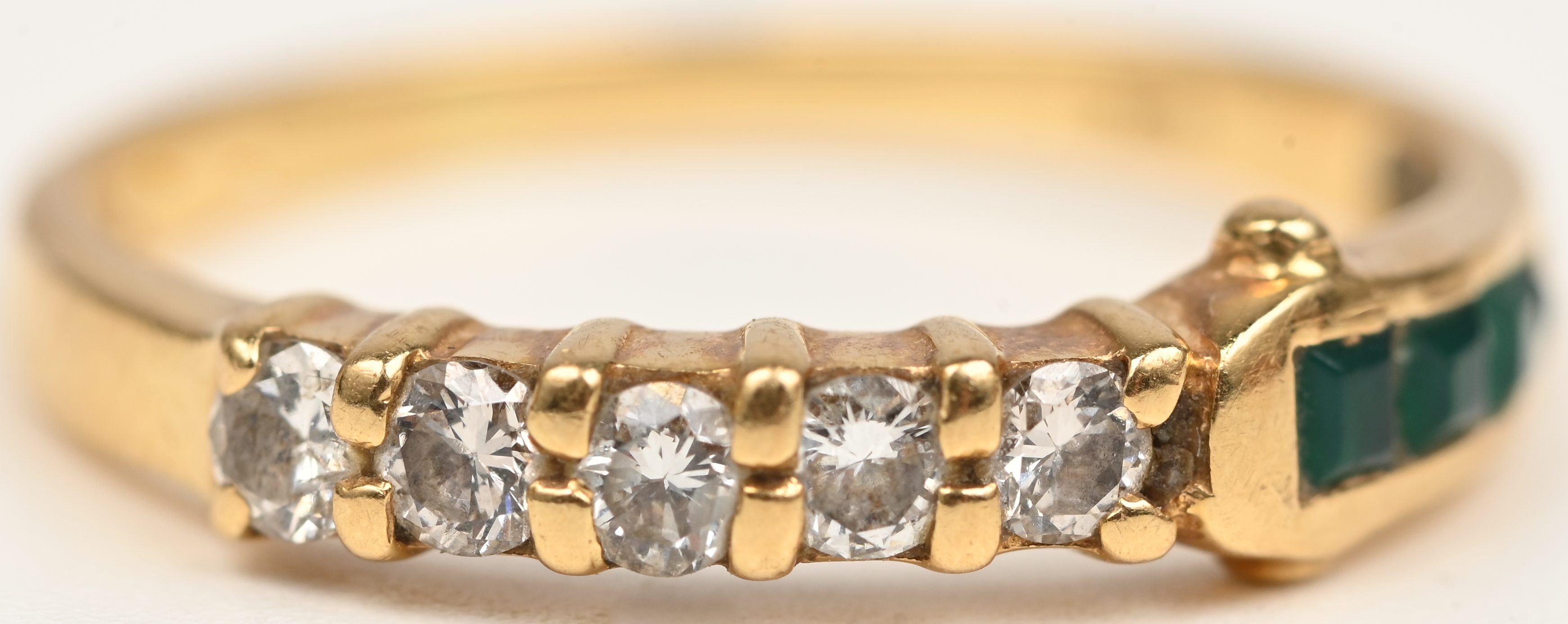 Een 18 kt geelgouden ring bezet met briljantjes en smaragd baguettes met een gezamenlijk gewicht van +- 0,20 ct Een 18 kt geelgouden ring bezet met briljantjes en smaragd baguettes met een gezamenlijk gewicht van +- 0,20 ct.
