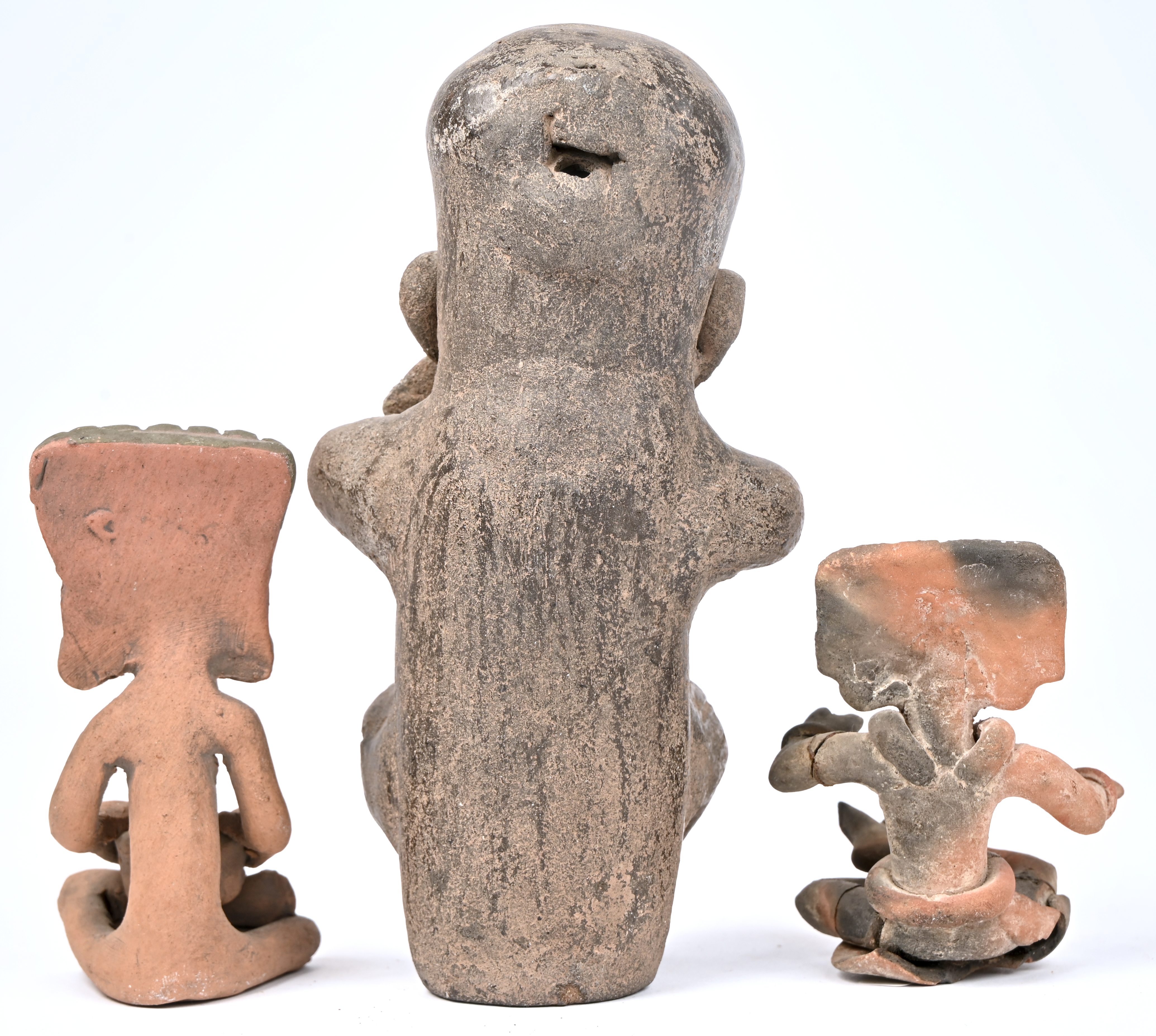 Drie aardewerken beeldjes van gezeten figuren met hoofdtooi en vaatwerk in de hand. In precolumbiaanse stijl Drie aardewerken beeldjes van gezeten figuren met hoofdtooi en vaatwerk in de hand. In precolumbiaanse stijl.