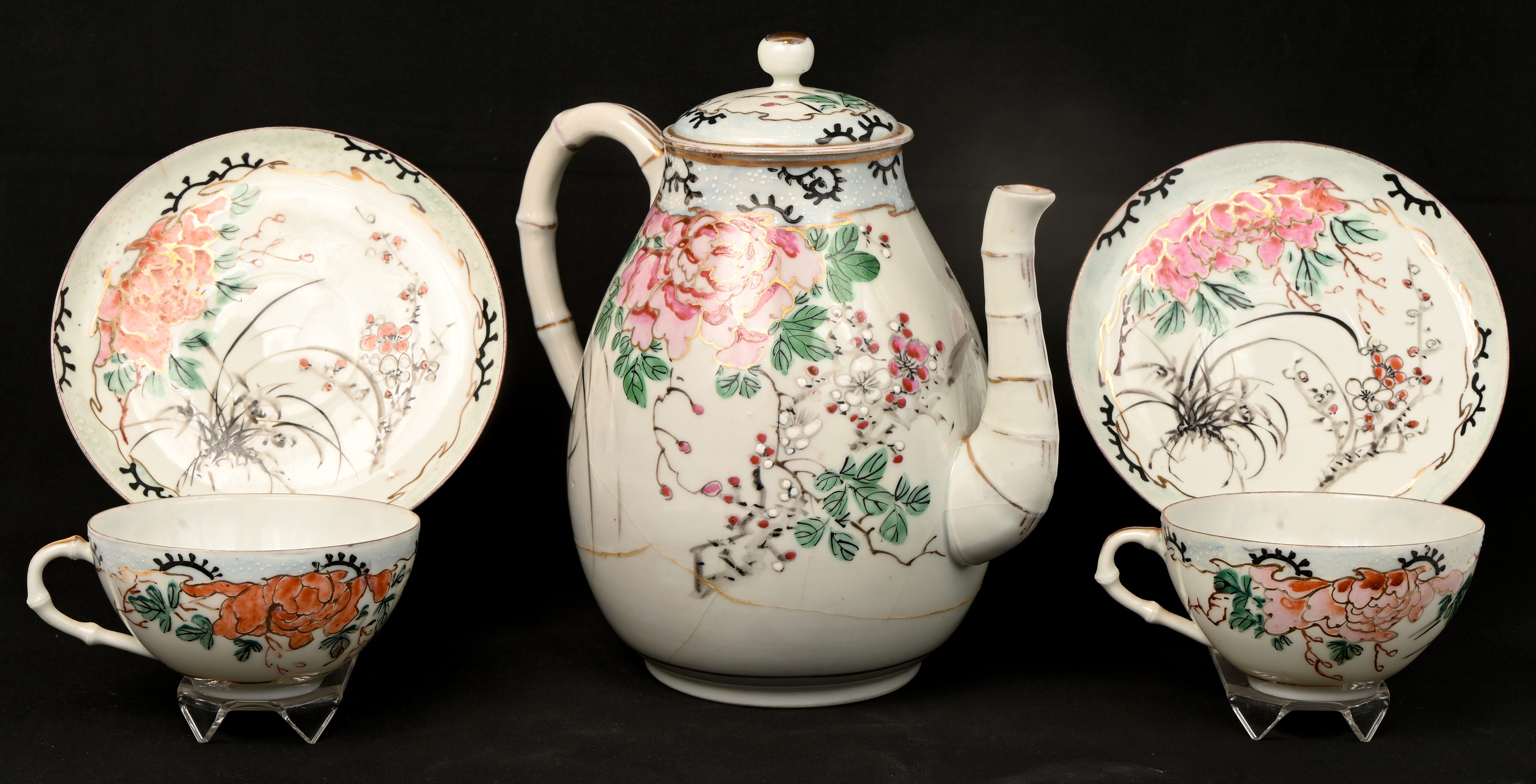 Een porseleinen theekan en twee kopjes en schoteltjes. Versierd in de geest van Kakeimon. Kan beschadigd Een porseleinen theekan en twee kopjes en schoteltjes. Versierd in de geest van Kakeimon. Kan beschadigd.