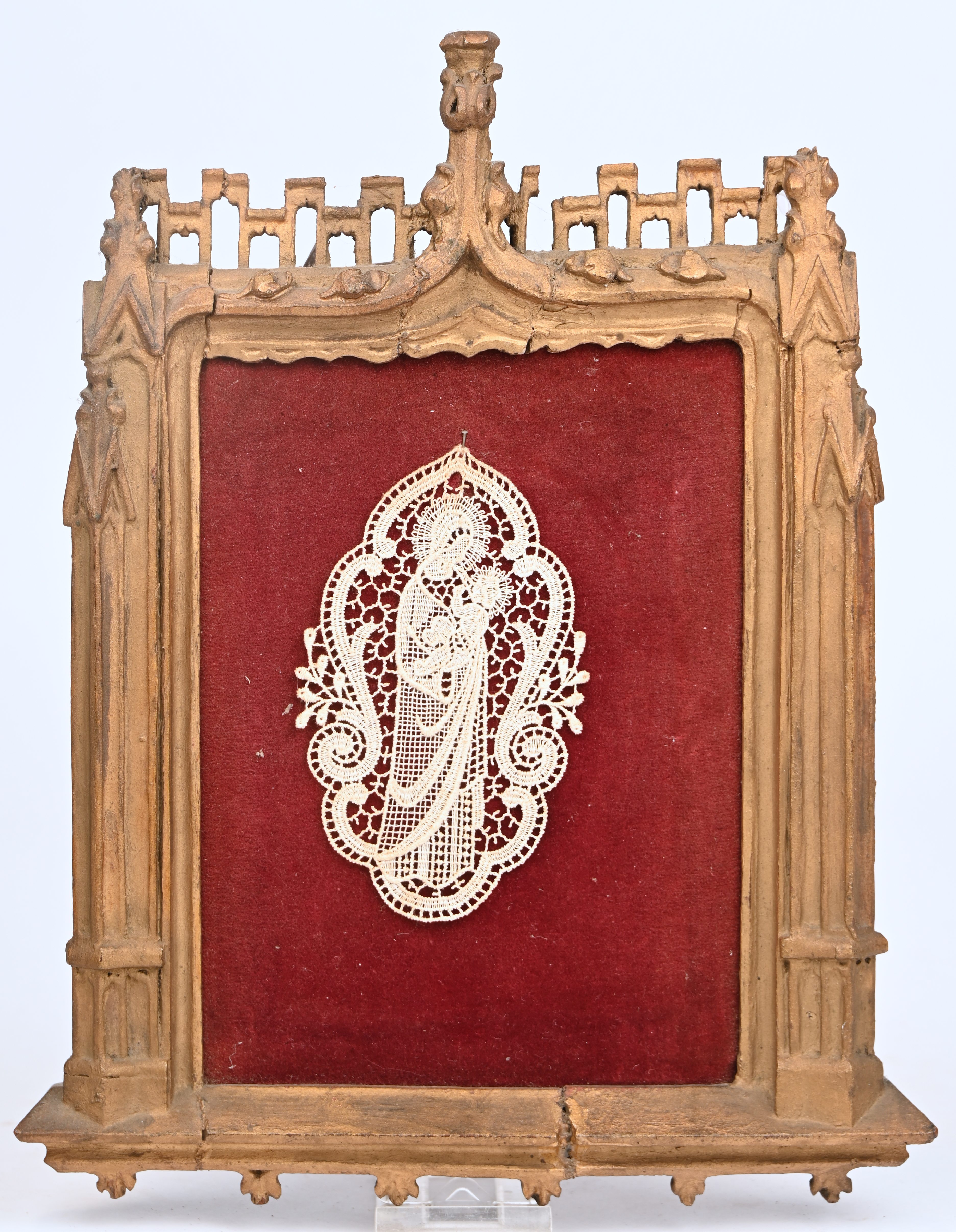 Een Madonna met kind van lintkant. In een houten lijst gebeeldhouwd in gotische stijl Een Madonna met kind van lintkant. In een houten lijst gebeeldhouwd in gotische stijl.