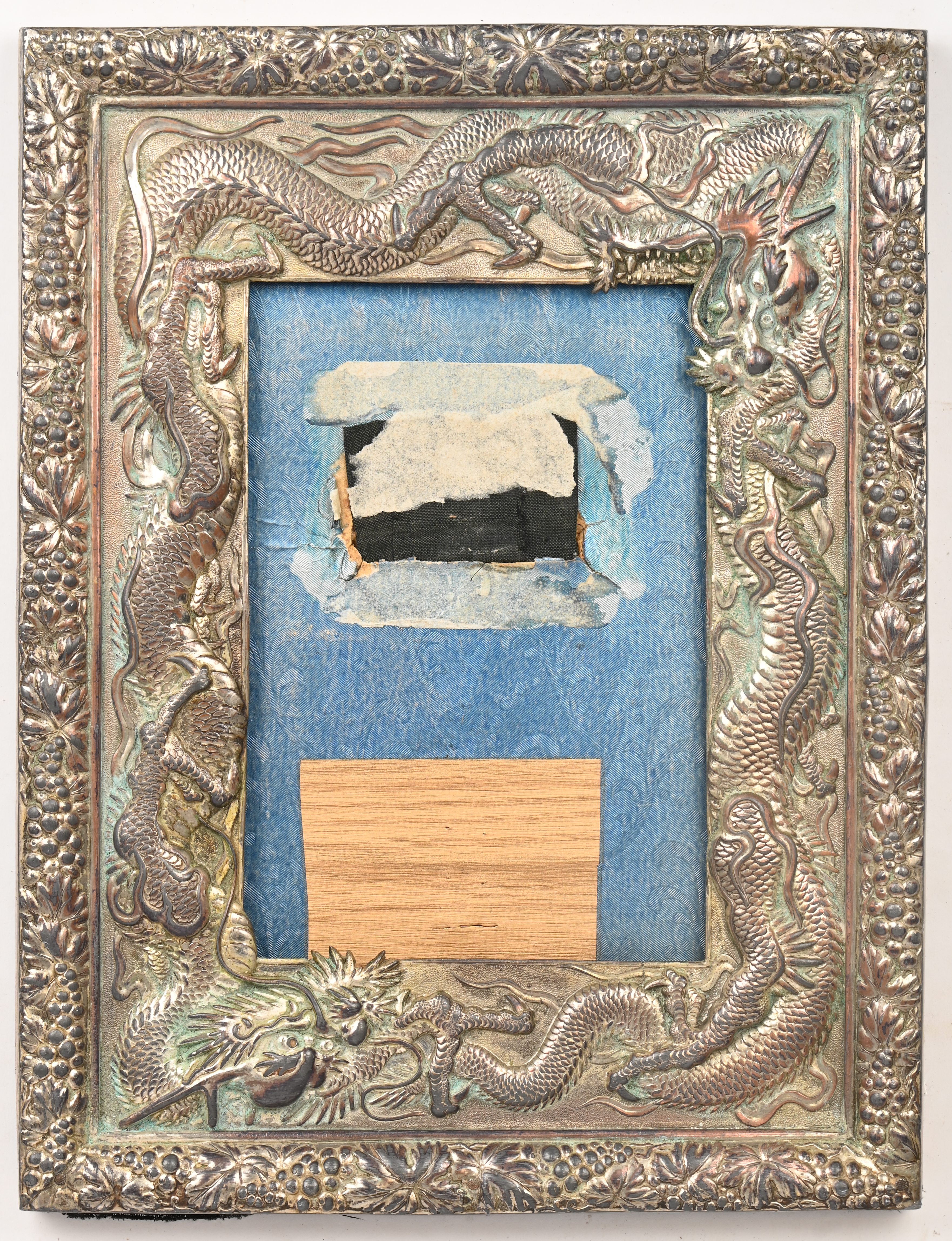 Een verzilverde kader met Chinese draken in relief. Binnenmaat 16,5 x 11 cm Een verzilverde kader met Chinese draken in relief. Binnenmaat 16,5 x 11 cm.