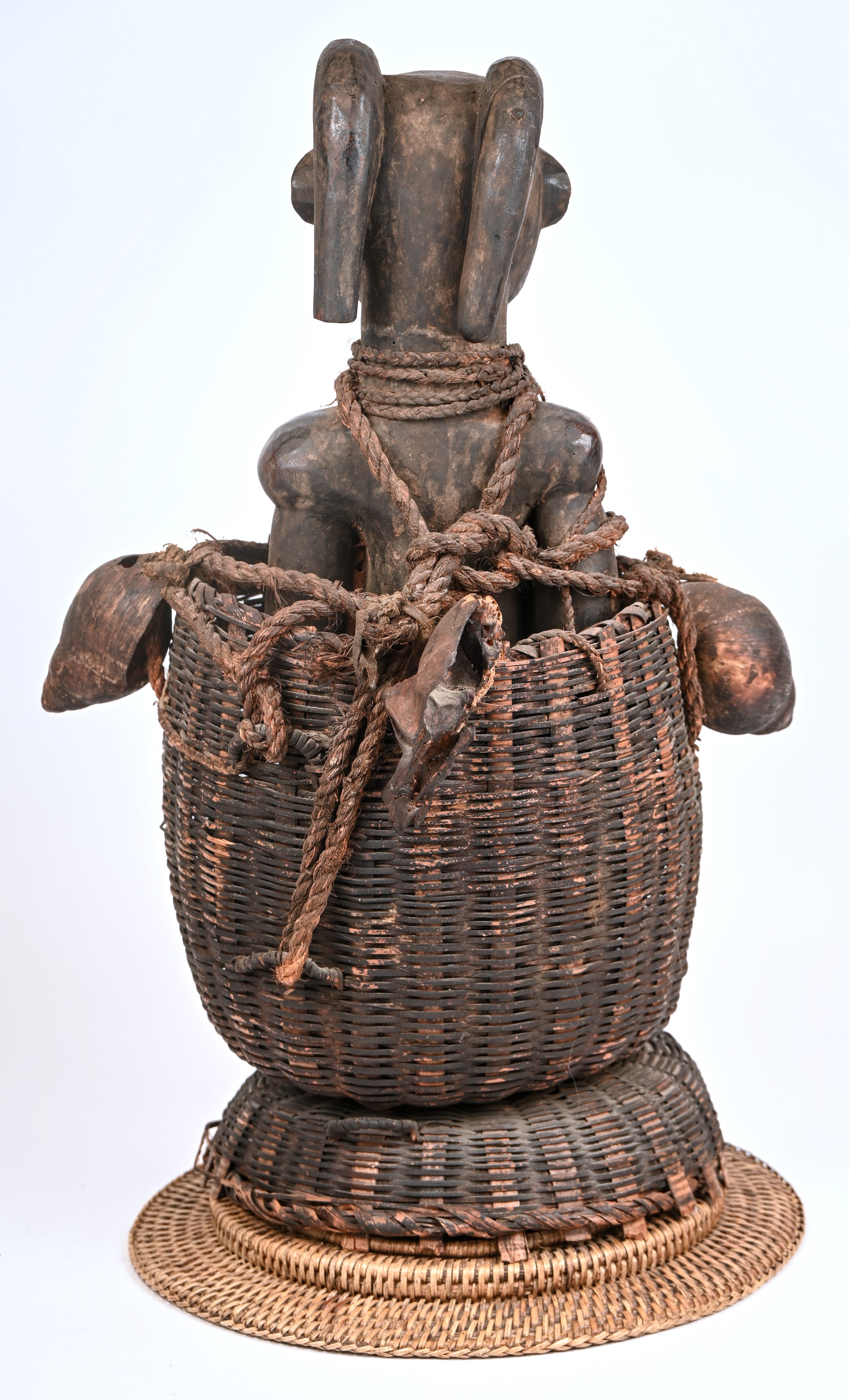 Een Afrikaans fetisjbeeld in een gevlochten mand, gedecoreerd met schelpen en apenschedels Een Afrikaans fetisjbeeld in een gevlochten mand, gedecoreerd met schelpen en apenschedels.