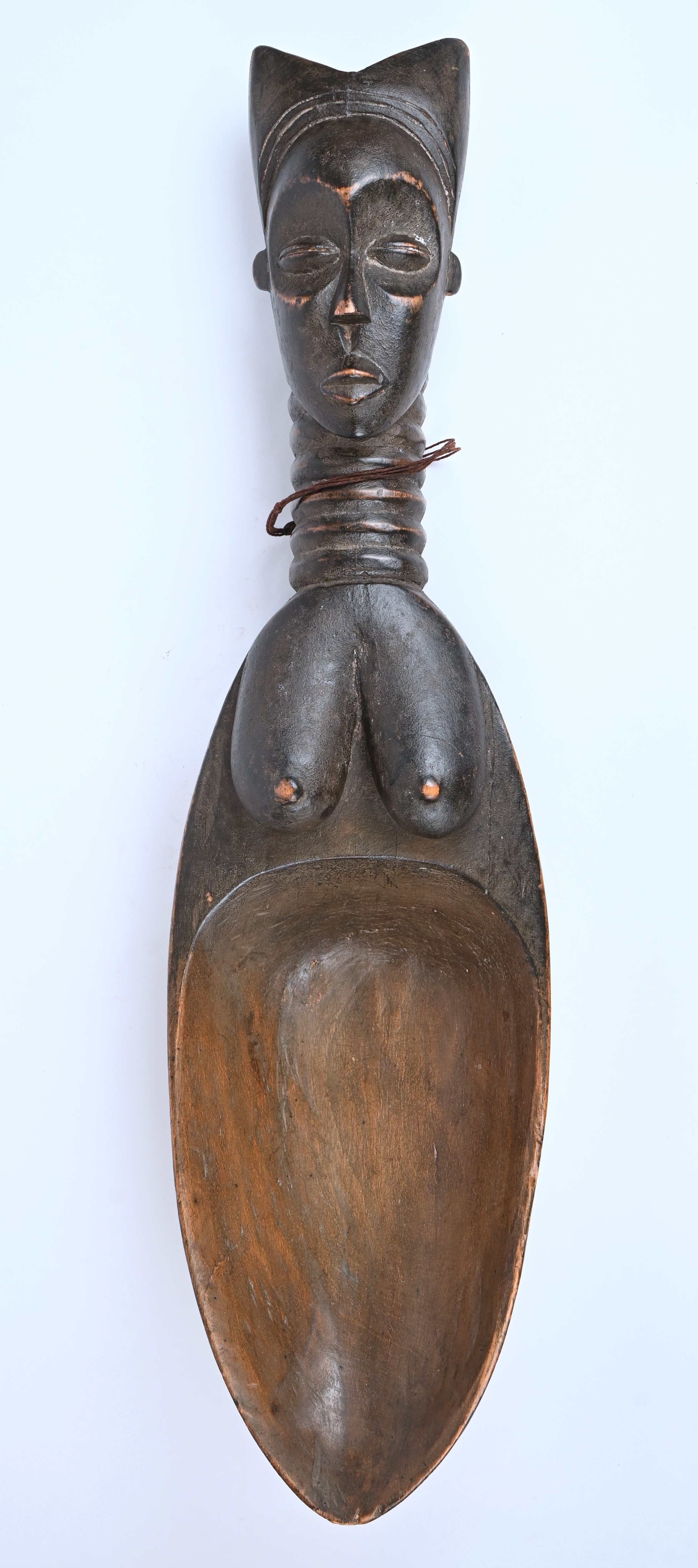Een Afrikaanse houten schaal in de vorm van een lepel met een vrouwentorso als handvat Een Afrikaanse houten schaal in de vorm van een lepel met een vrouwentorso als handvat.