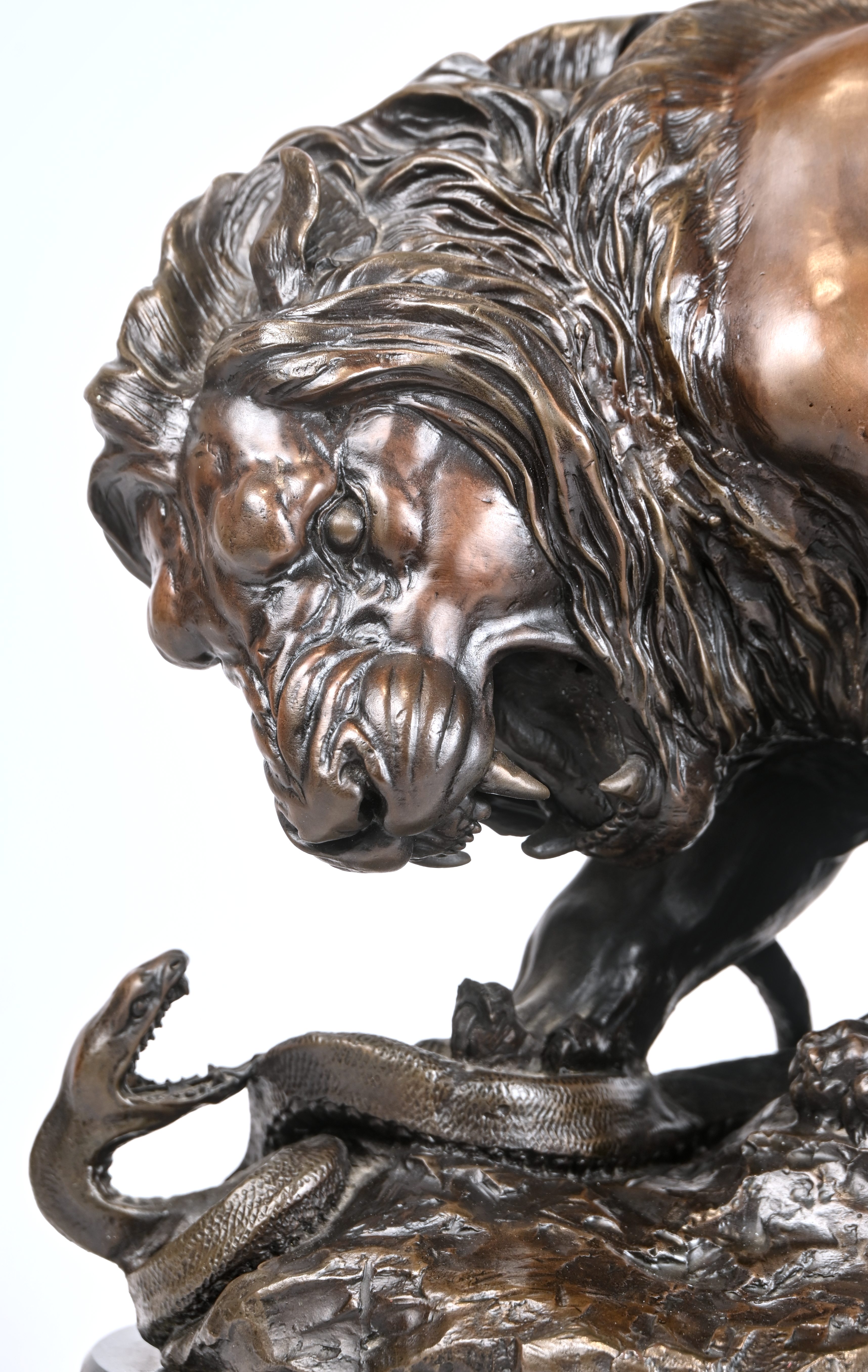 Een leeuw in gevecht met een slang, een gepatineerd bronzen beeld op marmeren voet. In de stijl van Antoine Louis Barye (1796-1875) Een leeuw in gevecht met een slang, een gepatineerd bronzen beeld op marmeren voet. In de stijl van Antoine Louis Barye (1796-1875).