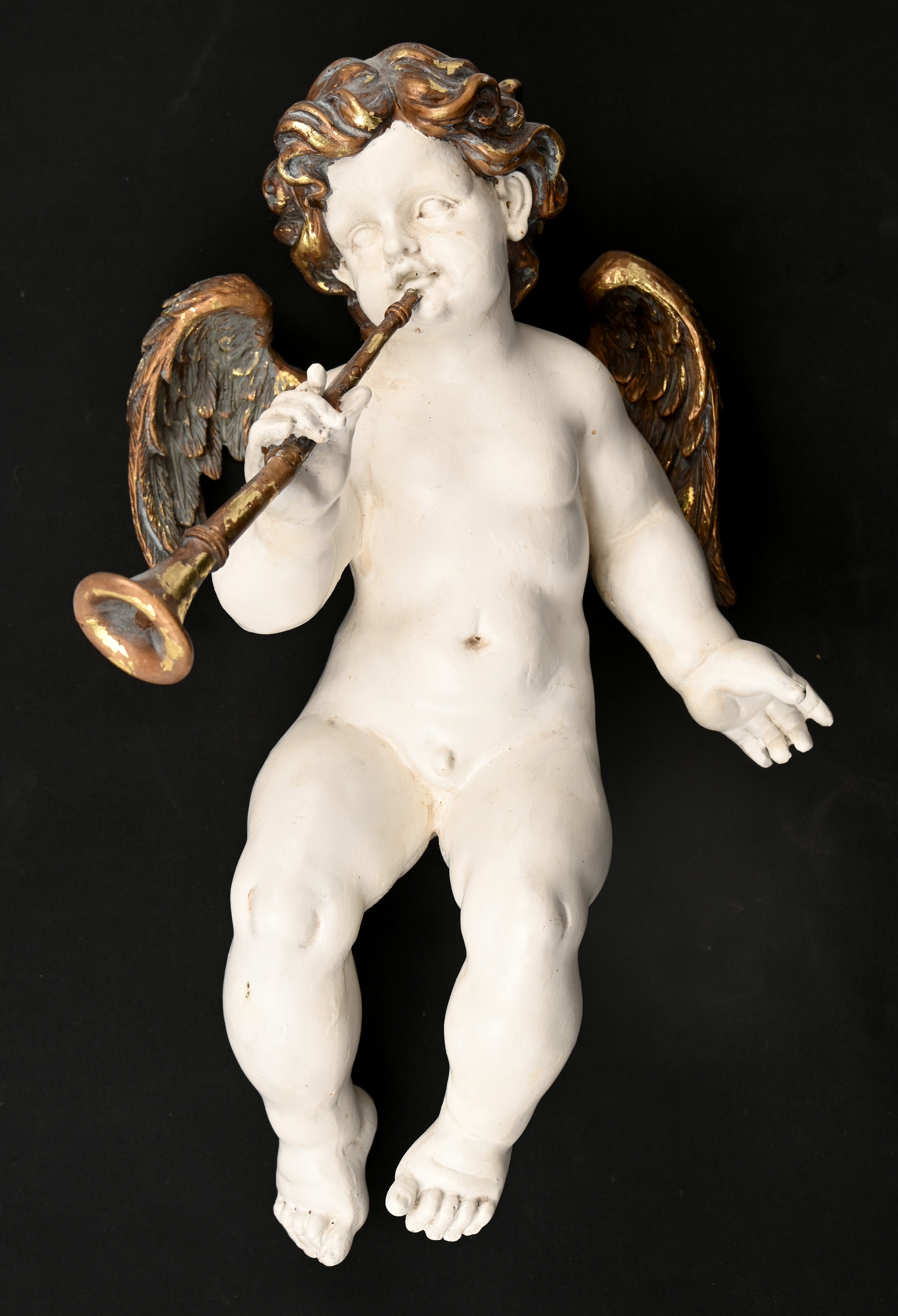 Een kunststoffen engel, wit met gouden accenten, restauratie aan de trompet Een kunststoffen engel, wit met gouden accenten, restauratie aan de trompet.