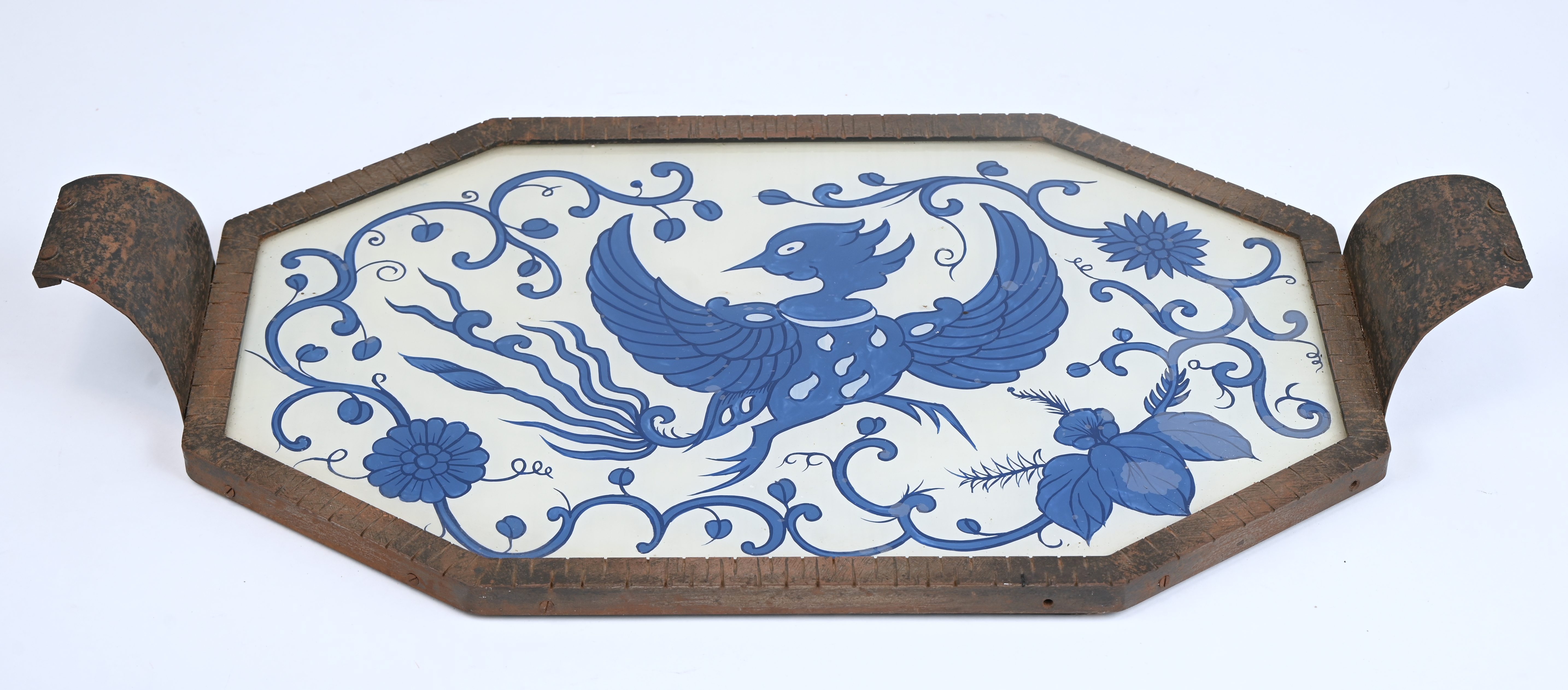 Een dienblad met blauwe feniks in églomisé techniek achter glas in smeedijzeren houder. Onderaan gesigneerd Een dienblad met blauwe feniks in églomisé techniek achter glas in smeedijzeren houder. Onderaan gesigneerd.