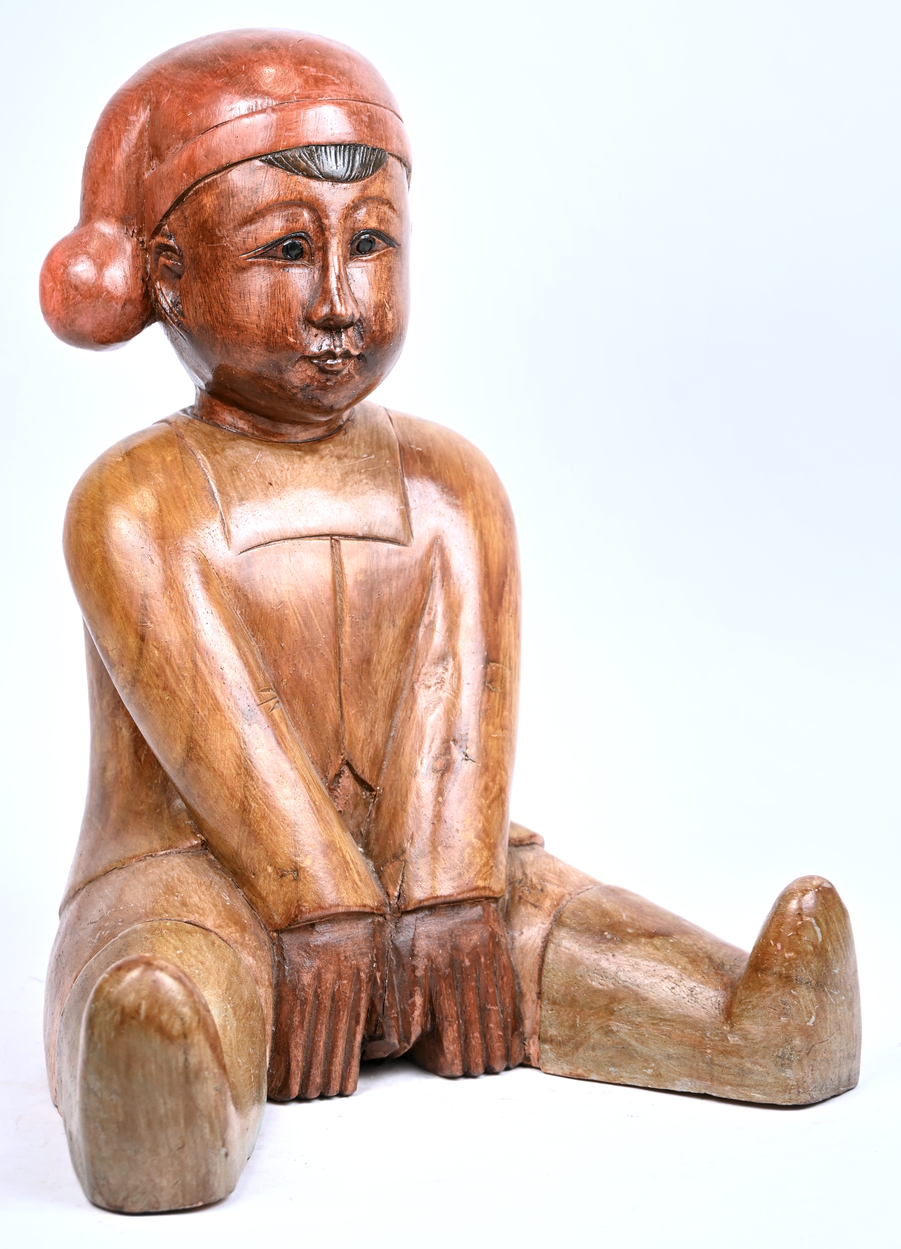 Een gepatineerd houten beeldje van een zittend figuur met slaapmuts. Vermoedelijk Aziatisch Een gepatineerd houten beeldje van een zittend figuur met slaapmuts. Vermoedelijk Aziatisch.
