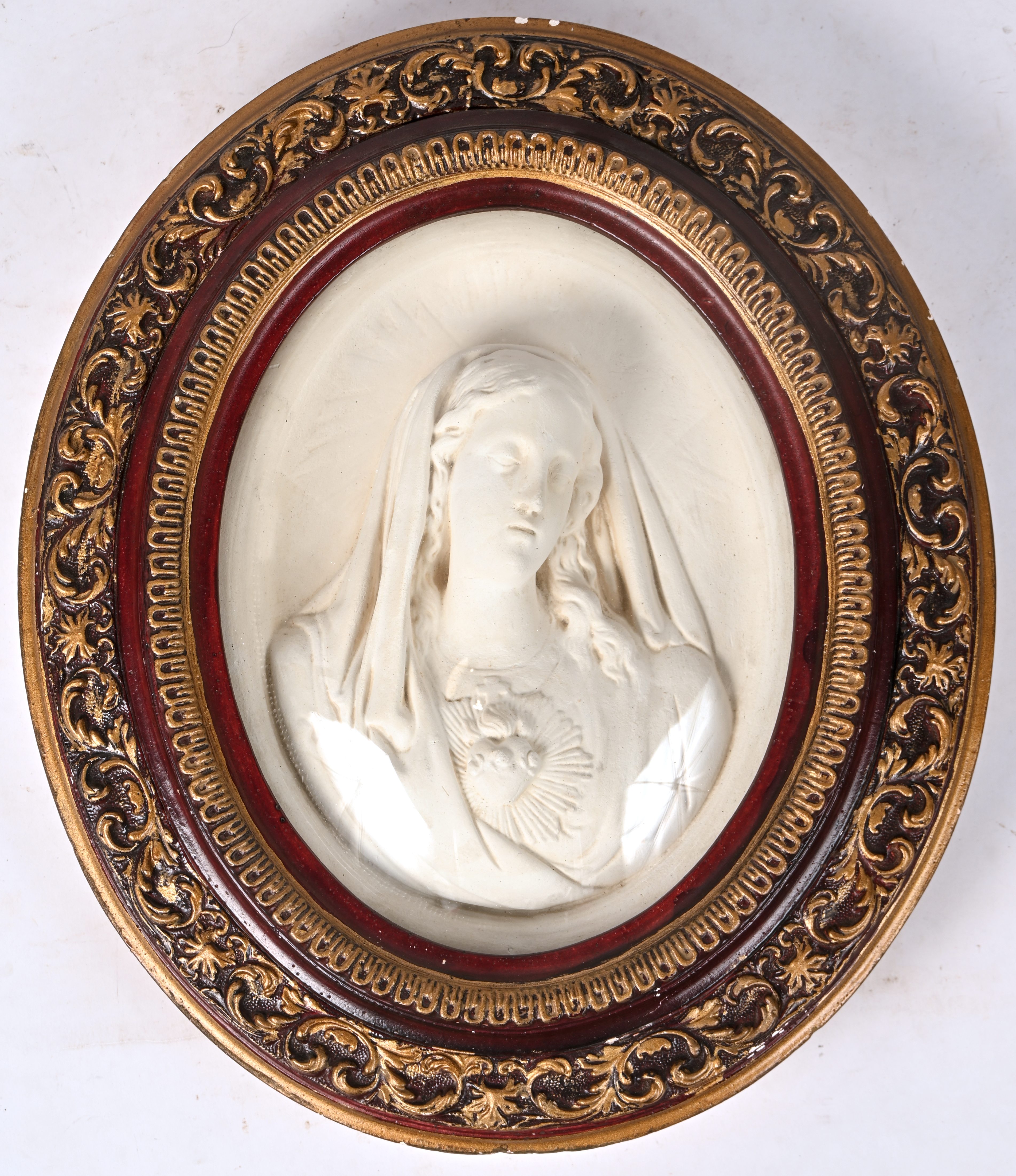 Een ovale kader waarin een plaasteren Madonna met heilig hart. Bol glas Een ovale kader waarin een plaasteren Madonna met heilig hart. Bol glas.