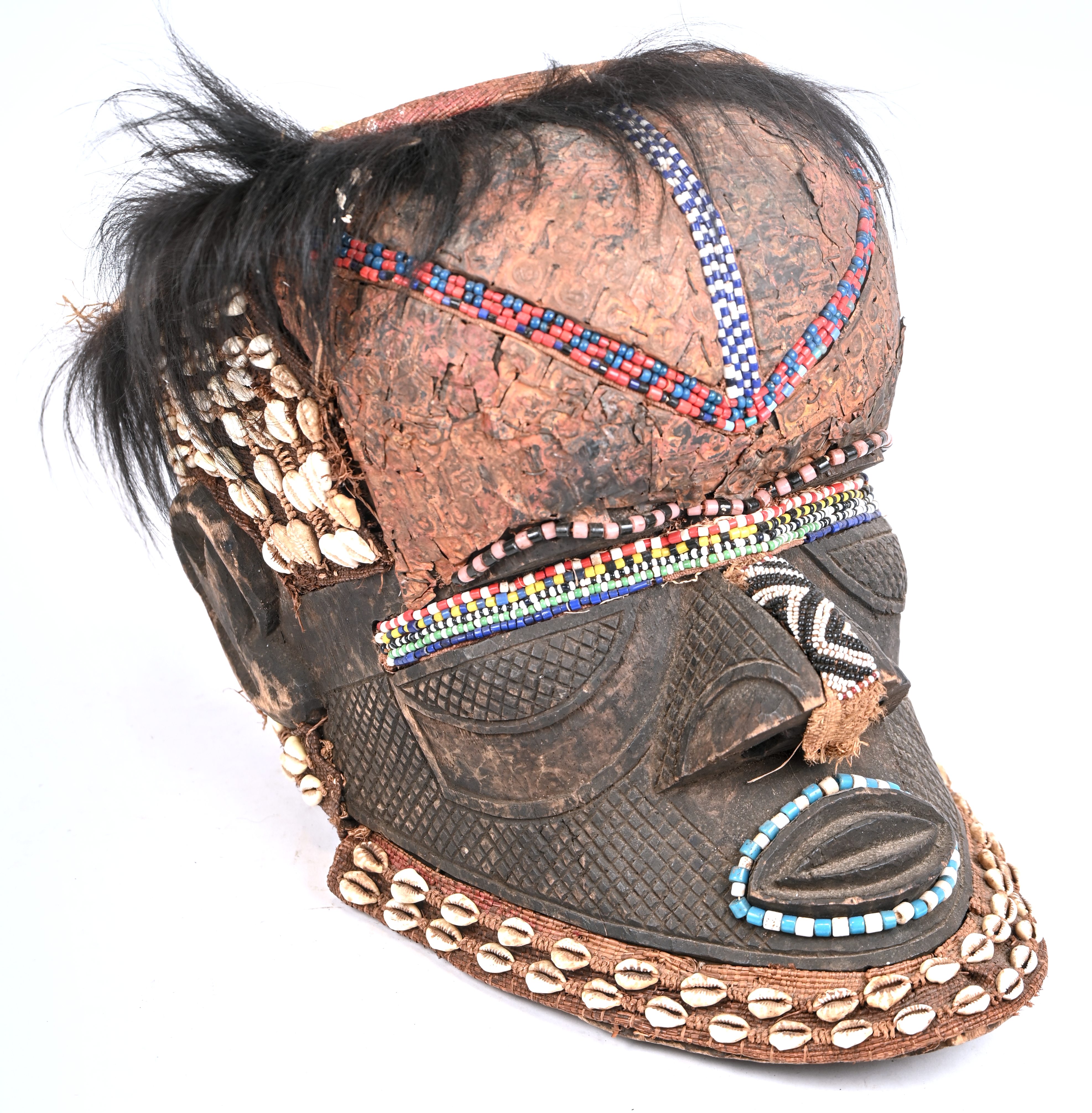 Een Afrikaans Kuba helmmasker bekleed met kralen, schelpjes en haar Een Afrikaans Kuba helmmasker bekleed met kralen, schelpjes en haar.