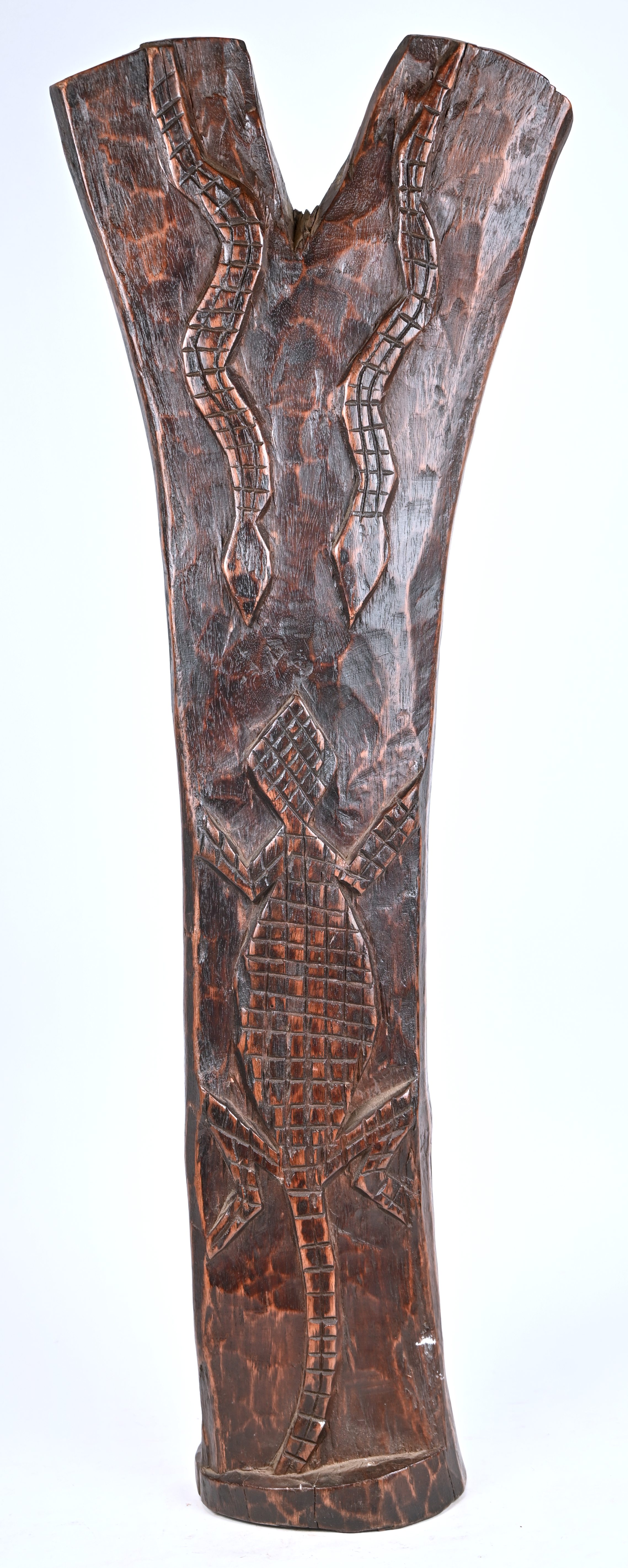 Een Afrikaans beeld van een man met gestrekte armen, van donker gepatineerd hout. Met op de rug een krokodil en twee slangen in bas relief Een Afrikaans beeld van een man met gestrekte armen, van donker gepatineerd hout. Met op de rug een krokodil en twee slangen in bas relief.