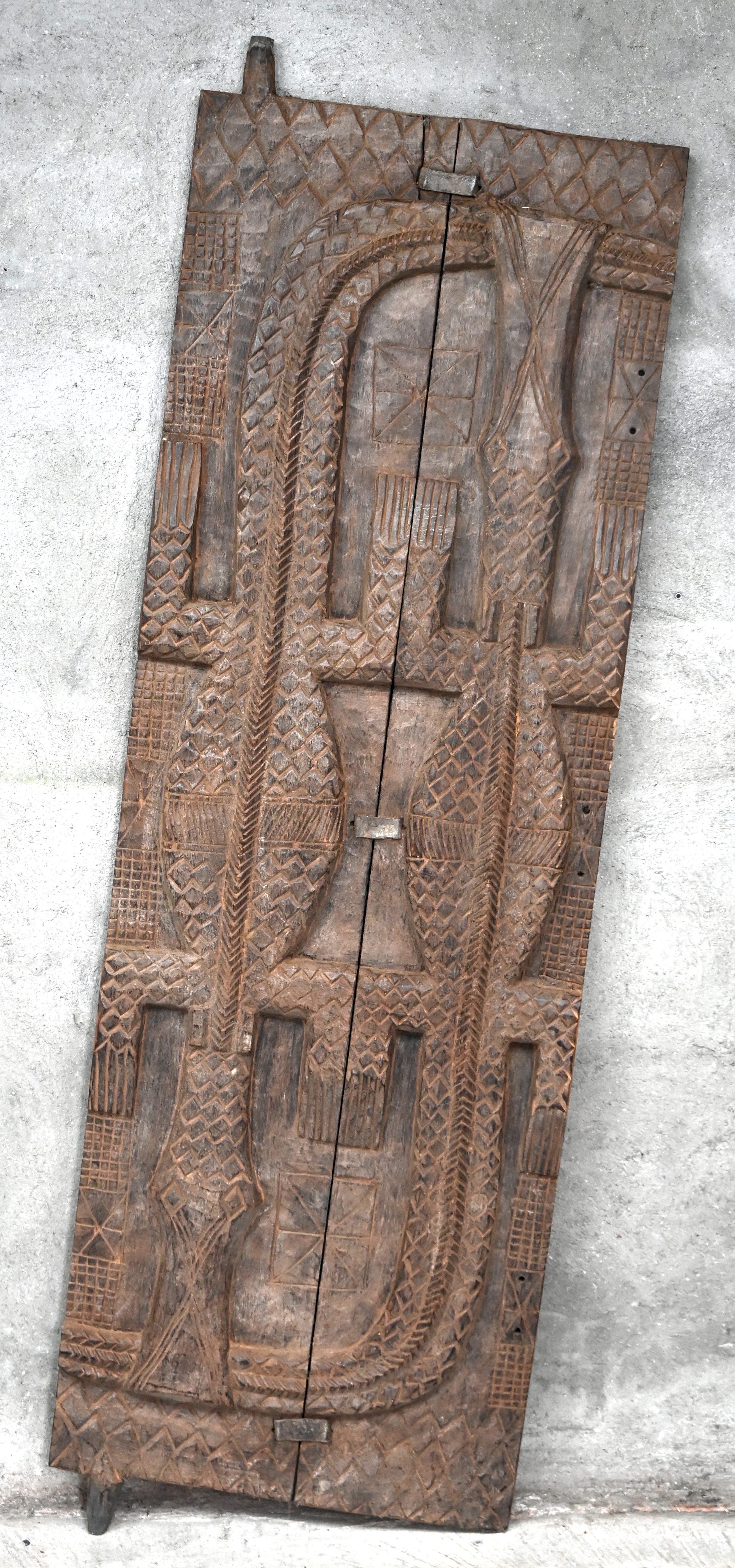 Een gesculpteerde graanschuurdeur van de Dogon uit Mali. Gedecoreerd met twee krokodillen die elkaar in de staart bijten Een gesculpteerde graanschuurdeur van de Dogon uit Mali. Gedecoreerd met twee krokodillen die elkaar in de staart bijten.