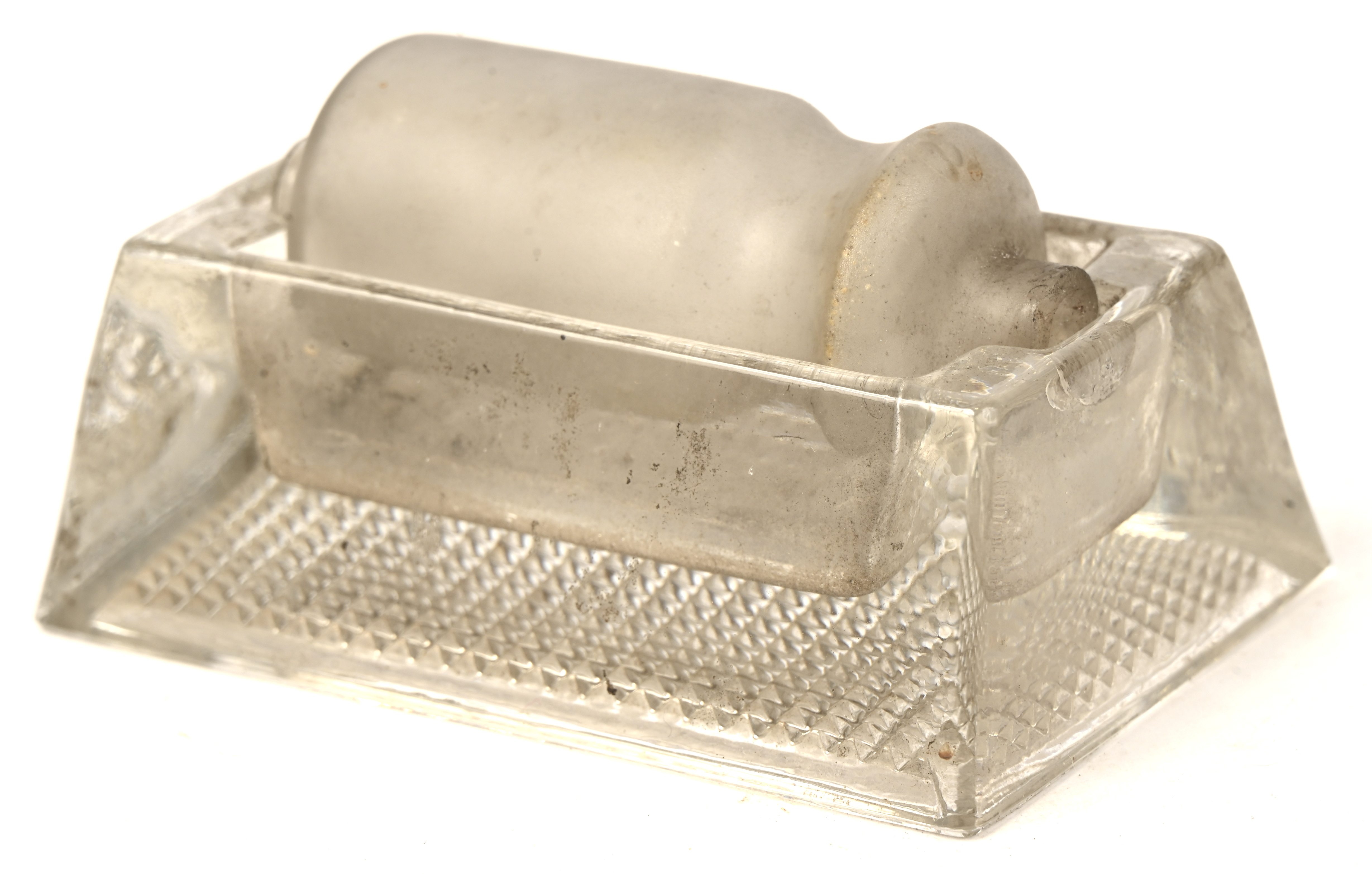 Een glazen postzegelbevochtiger. doorzichtig glazen rechthoekig bakje waarin een matglazen cylinder kan roteren Een glazen postzegelbevochtiger. doorzichtig glazen rechthoekig bakje waarin een matglazen cylinder kan roteren.