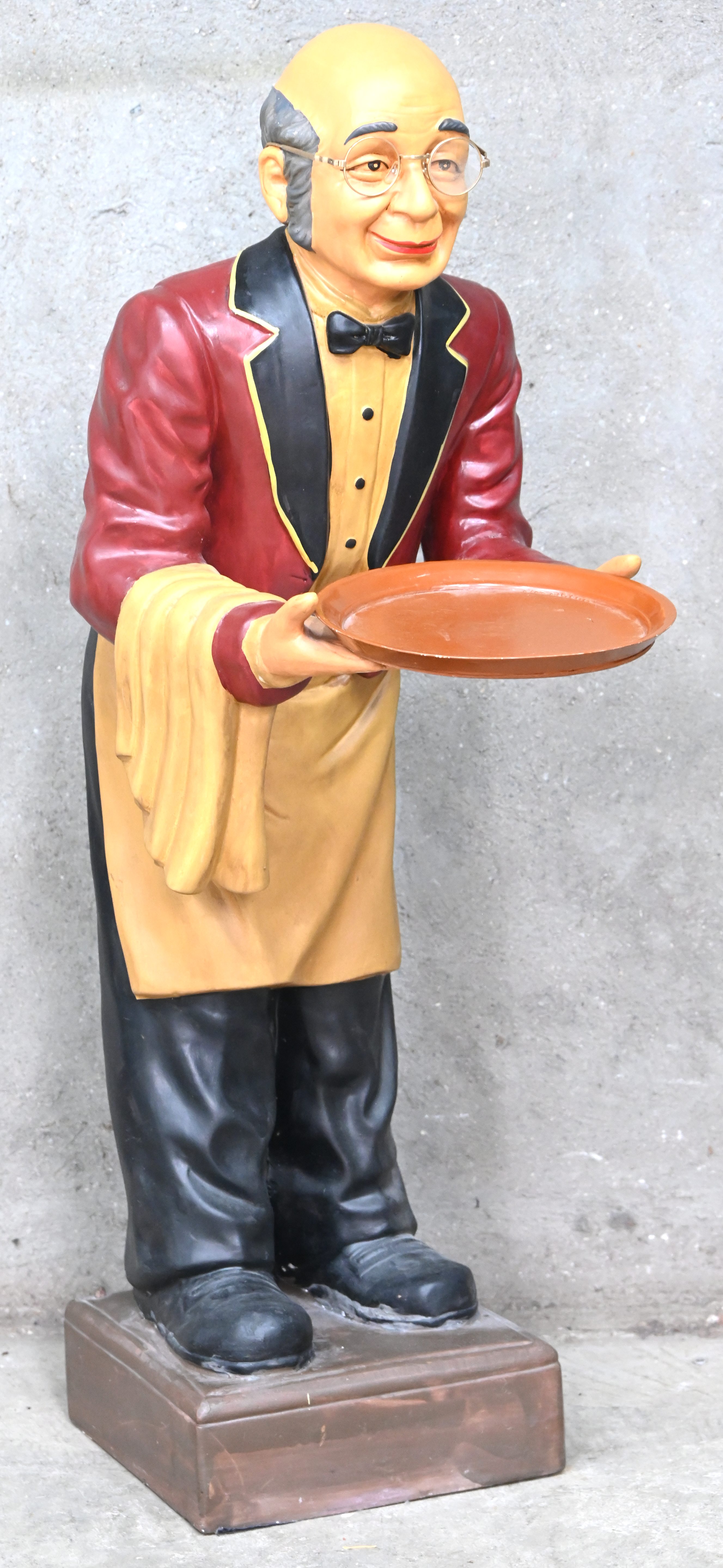 Een plaasteren butlerbeeld met een houten dienblad Een plaasteren butlerbeeld met een houten dienblad.