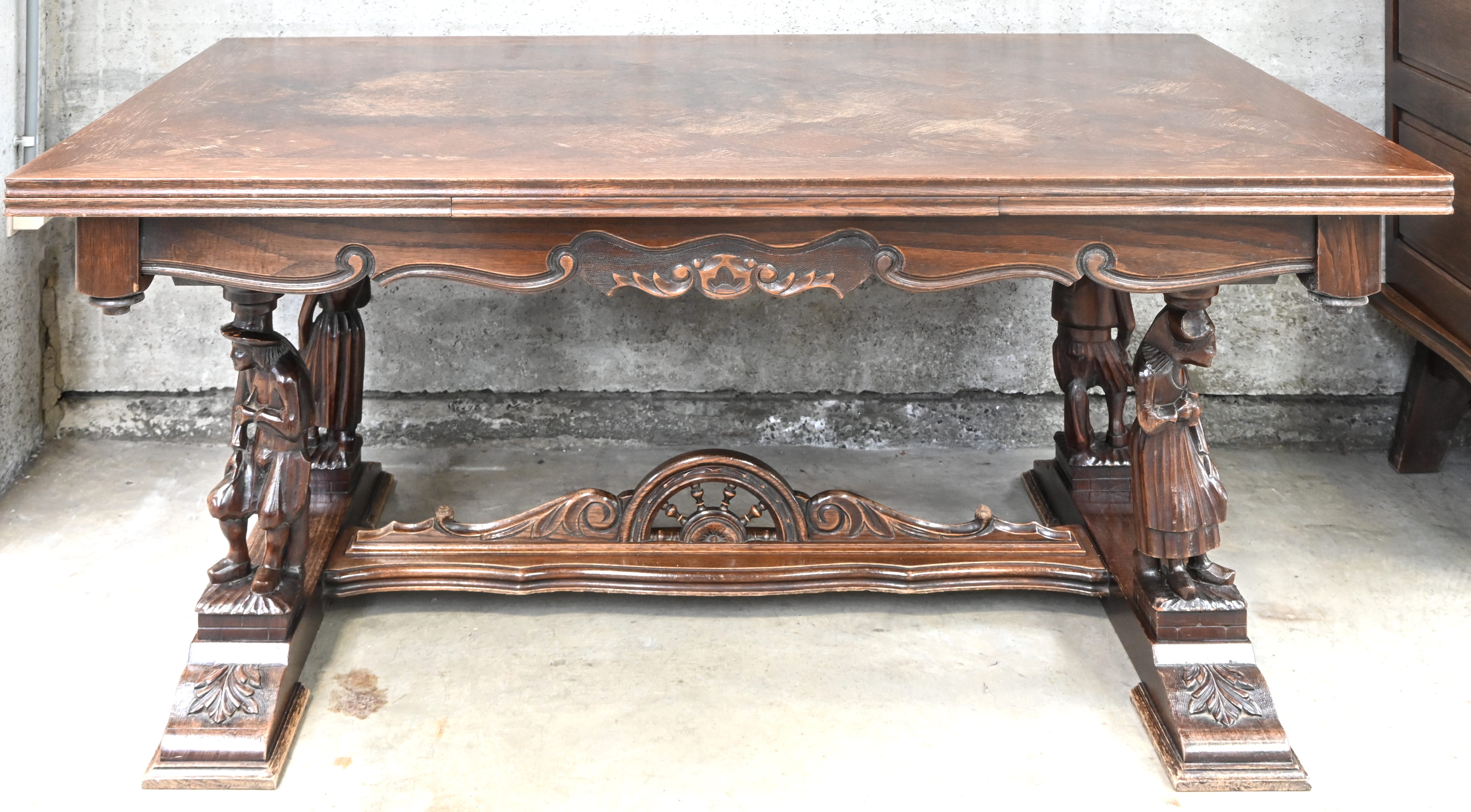 Een gesculpteerde houten tafel met figuren als tafelpoten. Waterschade aan het blad Een gesculpteerde houten tafel met figuren als tafelpoten. Waterschade aan het blad.
