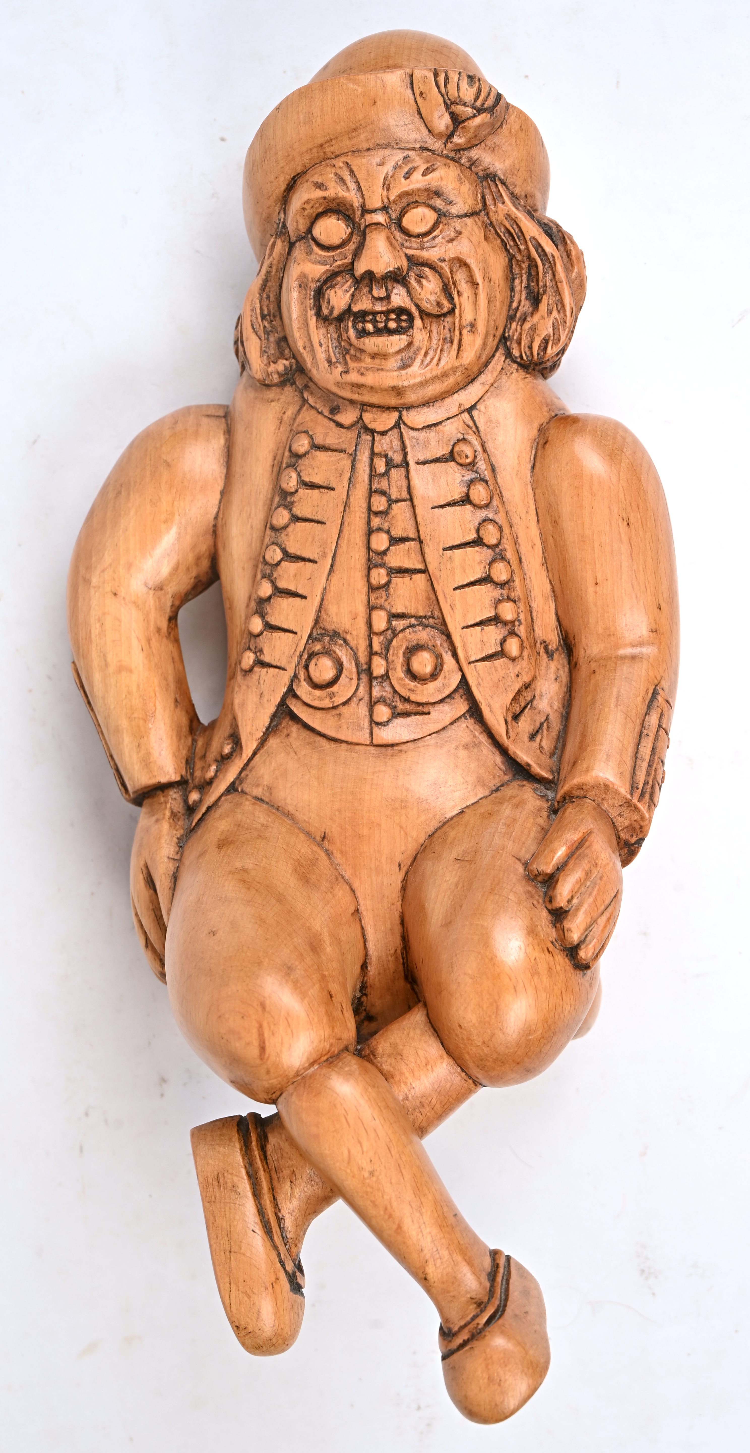 Een gesculpteerd eikenhouten beeldje van een zittende man in 19e eeuwse kledij Een gesculpteerd eikenhouten beeldje van een zittende man in 19e eeuwse kledij.