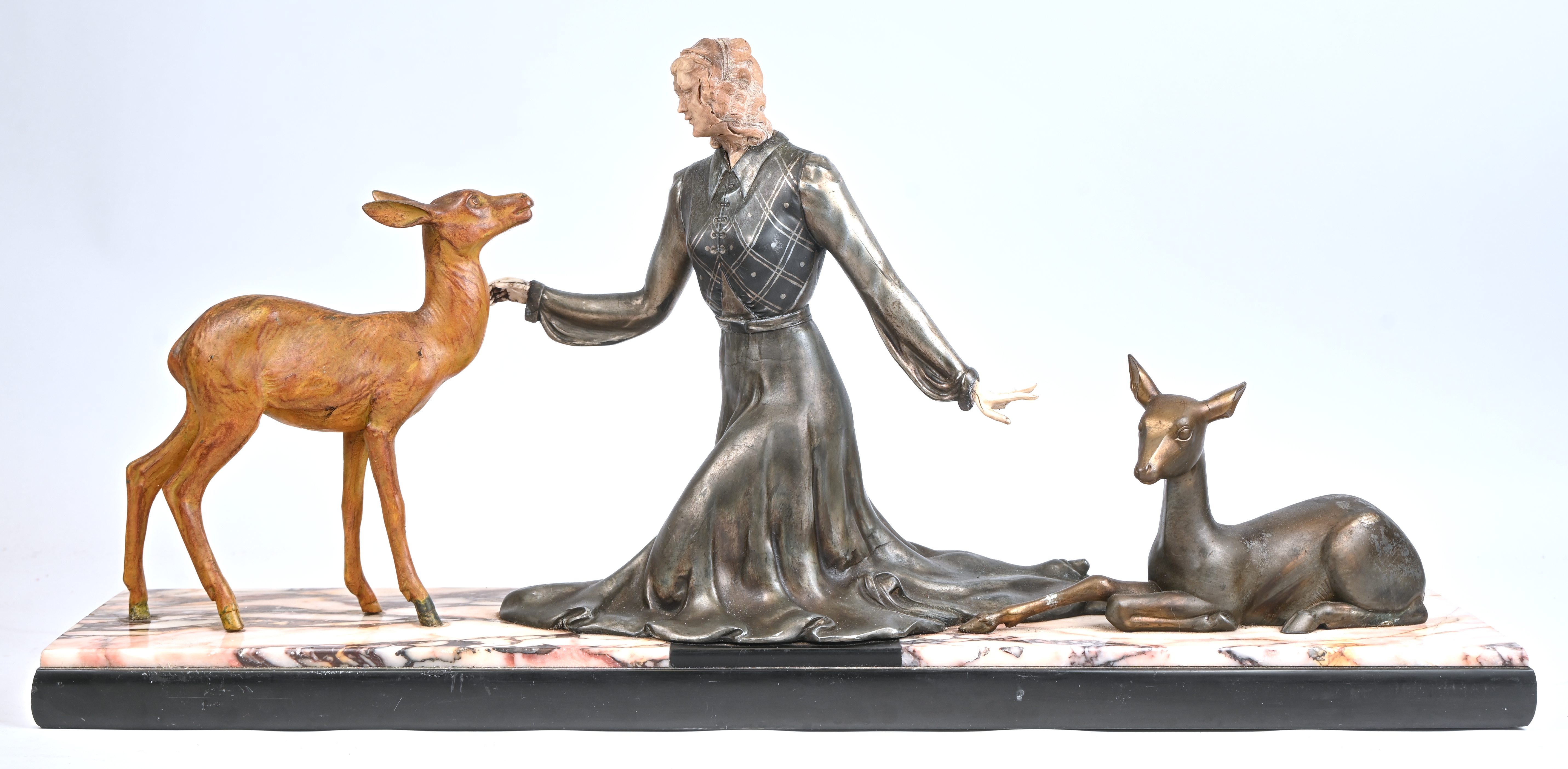 Een Art-Deco beeld van een jonge vrouw met twee hertjes. Gepatineerd zamak en marmer. Met schade aan het gelaad. Niet getekend Een Art-Deco beeld van een jonge vrouw met twee hertjes. Gepatineerd zamak en marmer. Met schade aan het gelaad. Niet getekend.