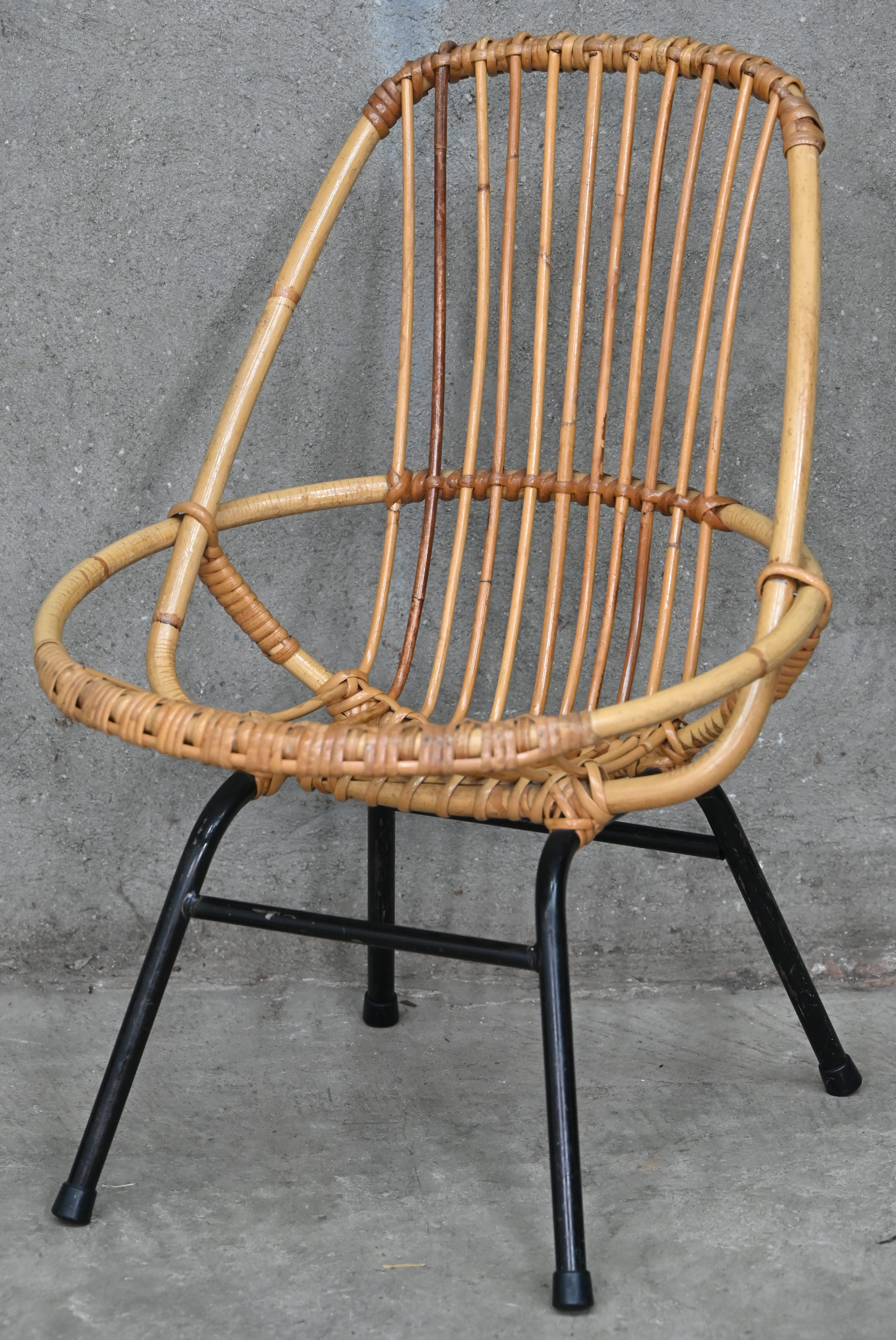 Een vintage kinderstoeltje, rotan op zwart metalen onderstel Een vintage kinderstoeltje, rotan op zwart metalen onderstel.