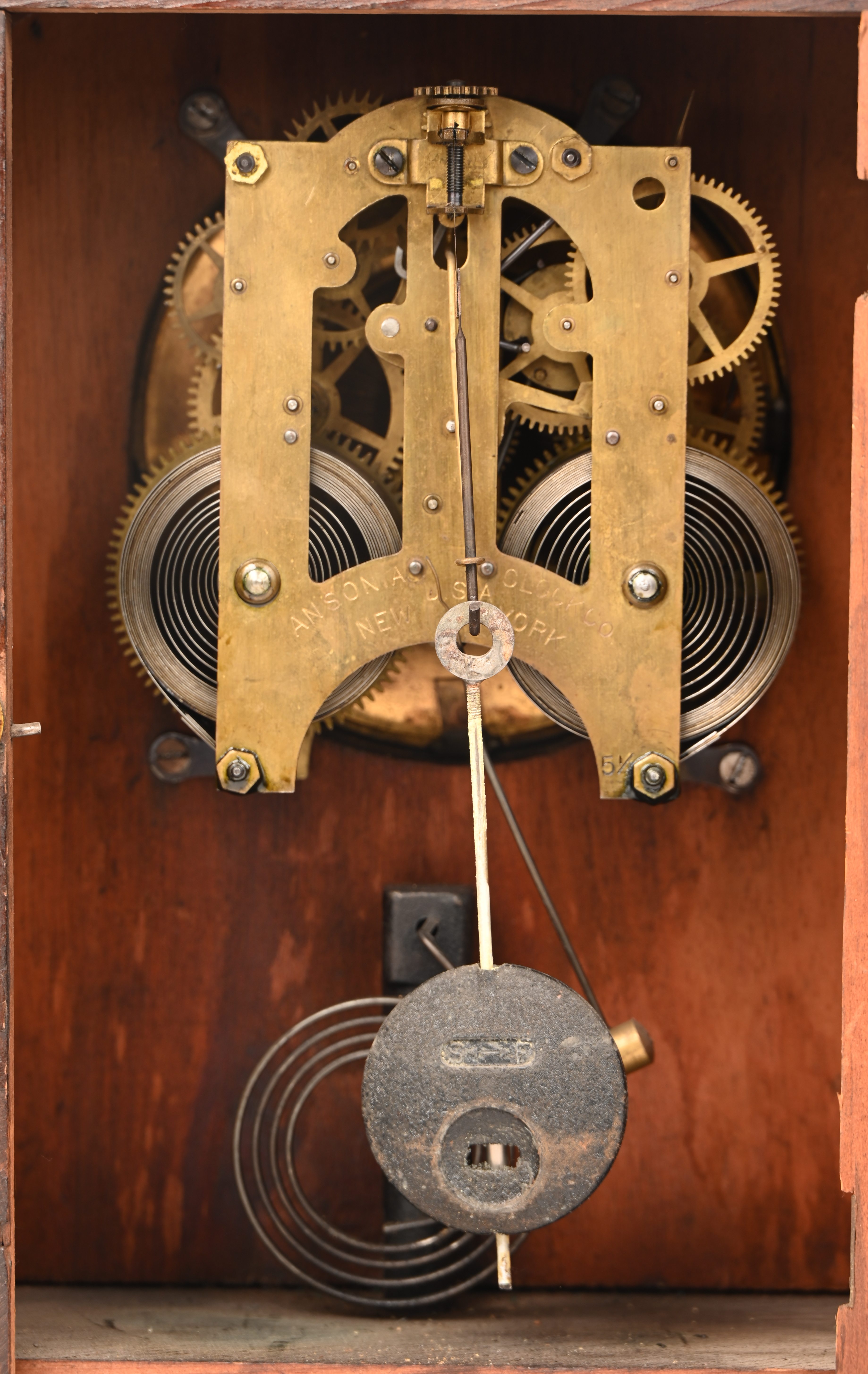 Een tafelklokje met houten kast, op het werk gemerkt Ansonia Clock Co, New York U.S.A Een tafelklokje met houten kast, op het werk gemerkt Ansonia Clock Co, New York U.S.A.