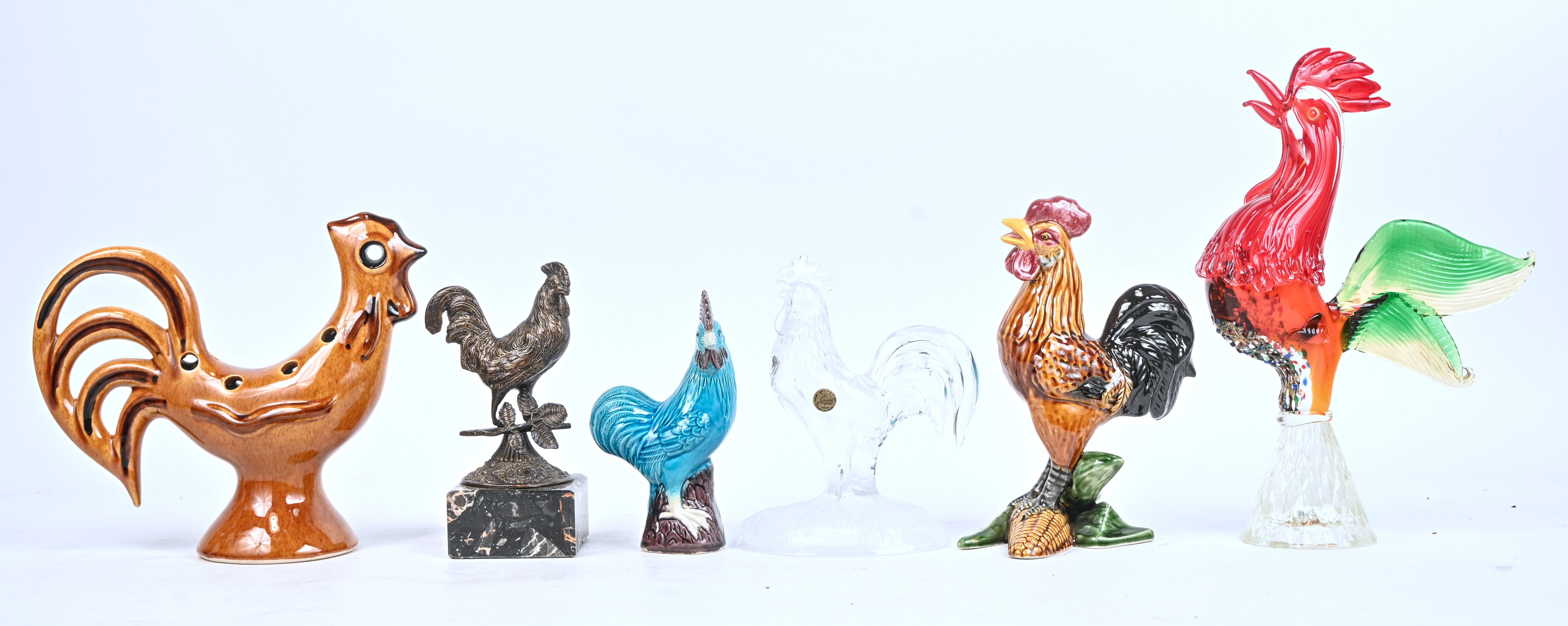 Zes hanen in diverse materialen, koper, kristal, Muranoglas, keramiek en porselein. Eén keramische met restauratie aan de maïskolf Zes hanen in diverse materialen, koper, kristal, Muranoglas, keramiek en porselein. Eén keramische met restauratie aan de maïskolf.