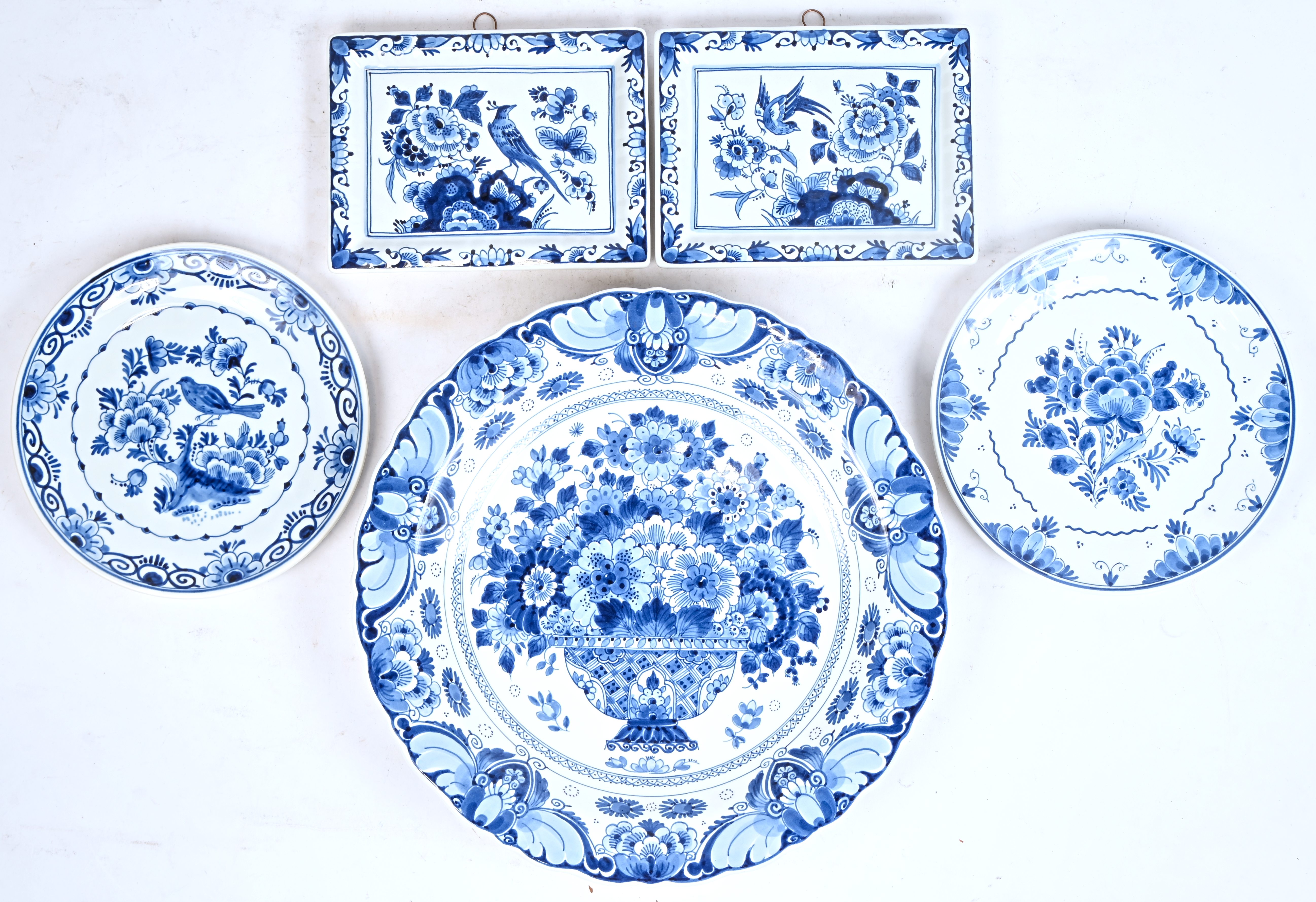 Twee rechthoekige schaaltjes, twee bordjes en een sierschotel van blauw-wit geglazuurd Delfts aardewerk. Gemerkt ‘De Porceleyne Fles’ Twee rechthoekige schaaltjes, twee bordjes en een sierschotel van blauw-wit geglazuurd Delfts aardewerk. Gemerkt ‘De Porceleyne Fles’.
