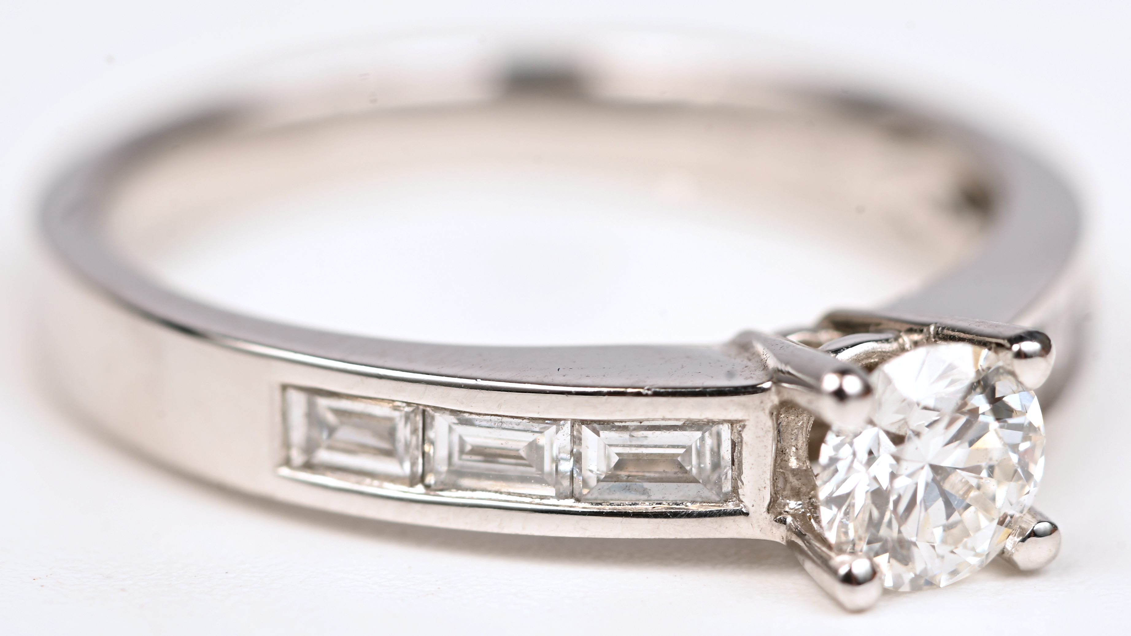 Een 18 kt witgouden ring bezet met centrale briljant +- 0,41 ct en diamantbaguetten met een gezamenlijk gewicht van +- 0,32 ct Een 18 kt witgouden ring bezet met centrale briljant +- 0,41 ct en diamantbaguetten met een gezamenlijk gewicht van +- 0,32 ct.