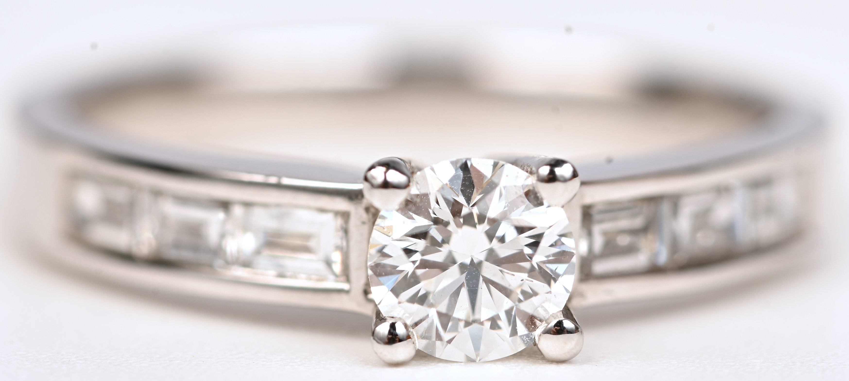 Een 18 kt witgouden ring bezet met centrale briljant +- 0,41 ct en diamantbaguetten met een gezamenlijk gewicht van +- 0,32 ct Een 18 kt witgouden ring bezet met centrale briljant +- 0,41 ct en diamantbaguetten met een gezamenlijk gewicht van +- 0,32 ct.