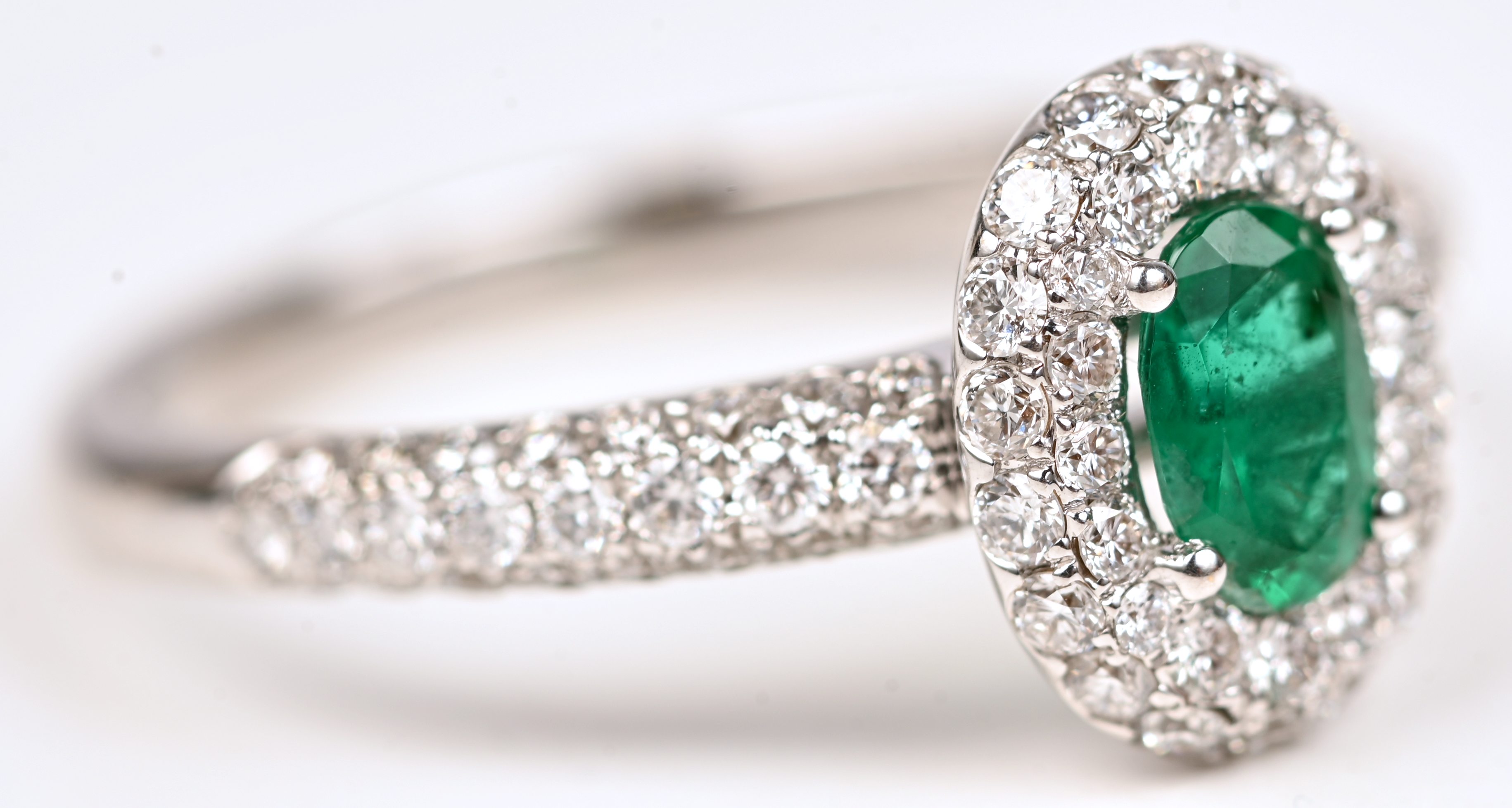 Een 18 kt witgouden ring bezet met centrale smaragd van +- 0,40 ct. en briljanten met een gezamenlijk gewicht van +- 0,75 ct Een 18 kt witgouden ring bezet met centrale smaragd van +- 0,40 ct. en briljanten met een gezamenlijk gewicht van +- 0,75 ct.