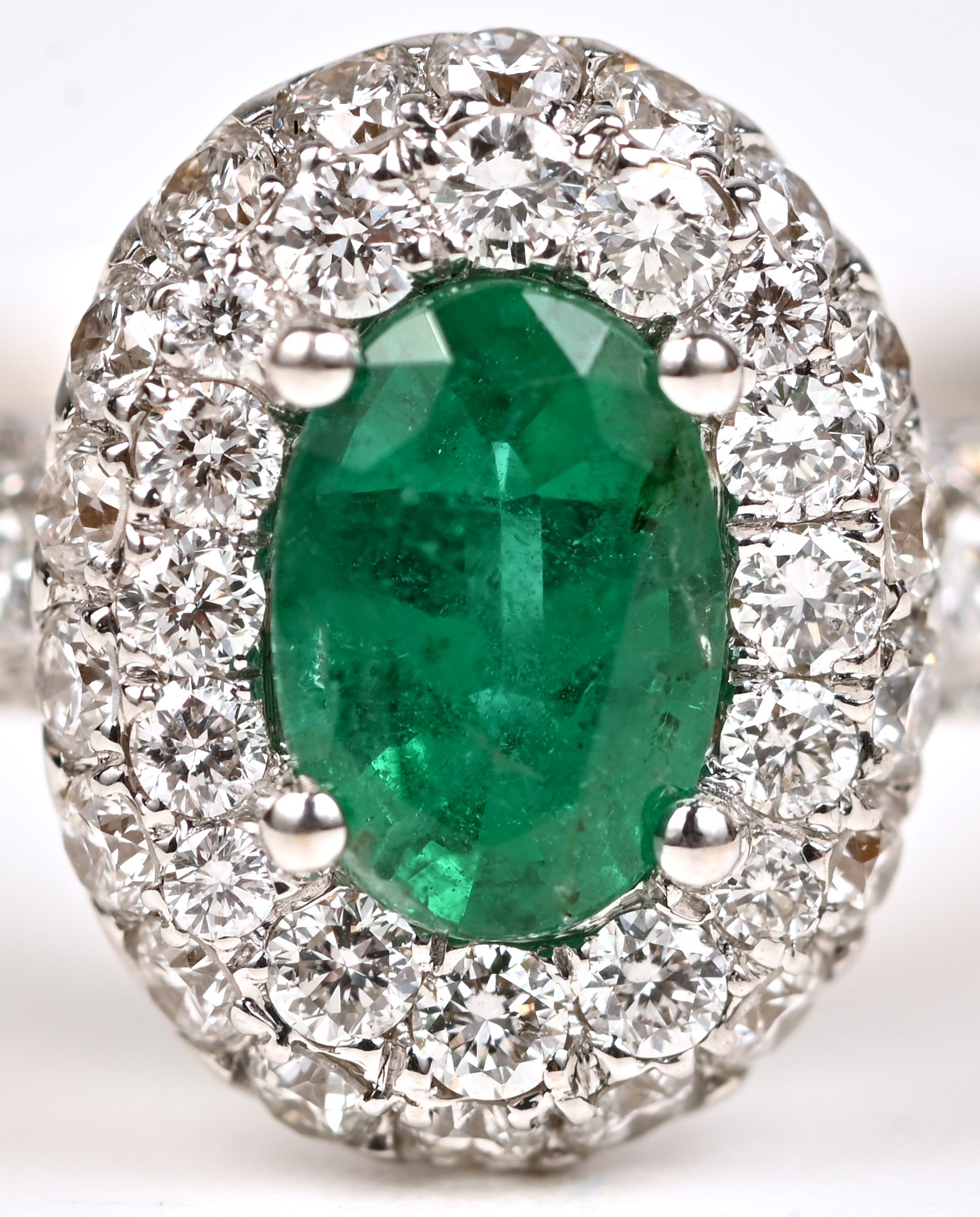 Een 18 kt witgouden ring bezet met centrale smaragd van +- 0,40 ct. en briljanten met een gezamenlijk gewicht van +- 0,75 ct Een 18 kt witgouden ring bezet met centrale smaragd van +- 0,40 ct. en briljanten met een gezamenlijk gewicht van +- 0,75 ct.