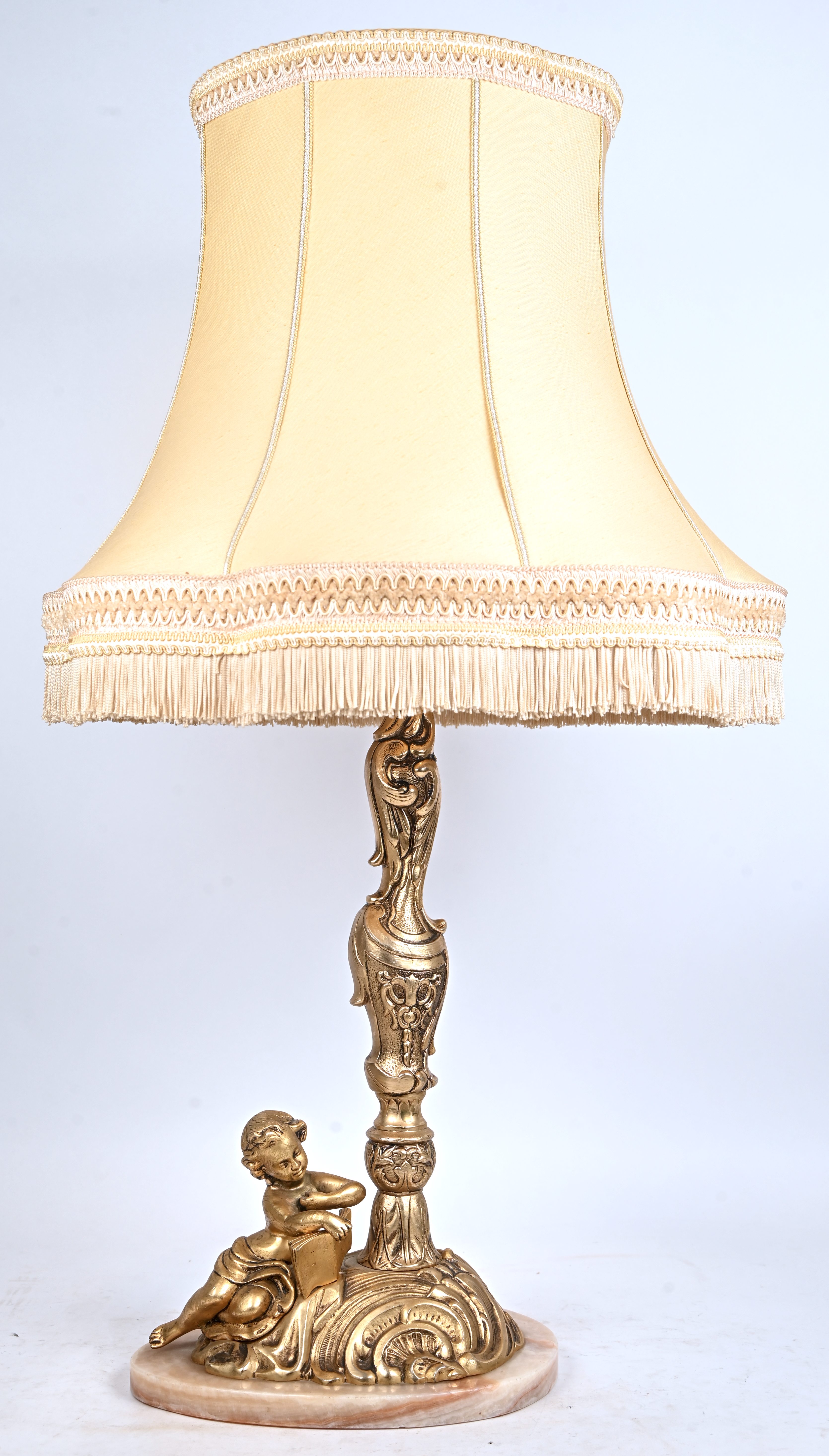 Een messing tafellamp met lezende putti op de voet Een messing tafellamp met lezende putti op de voet.