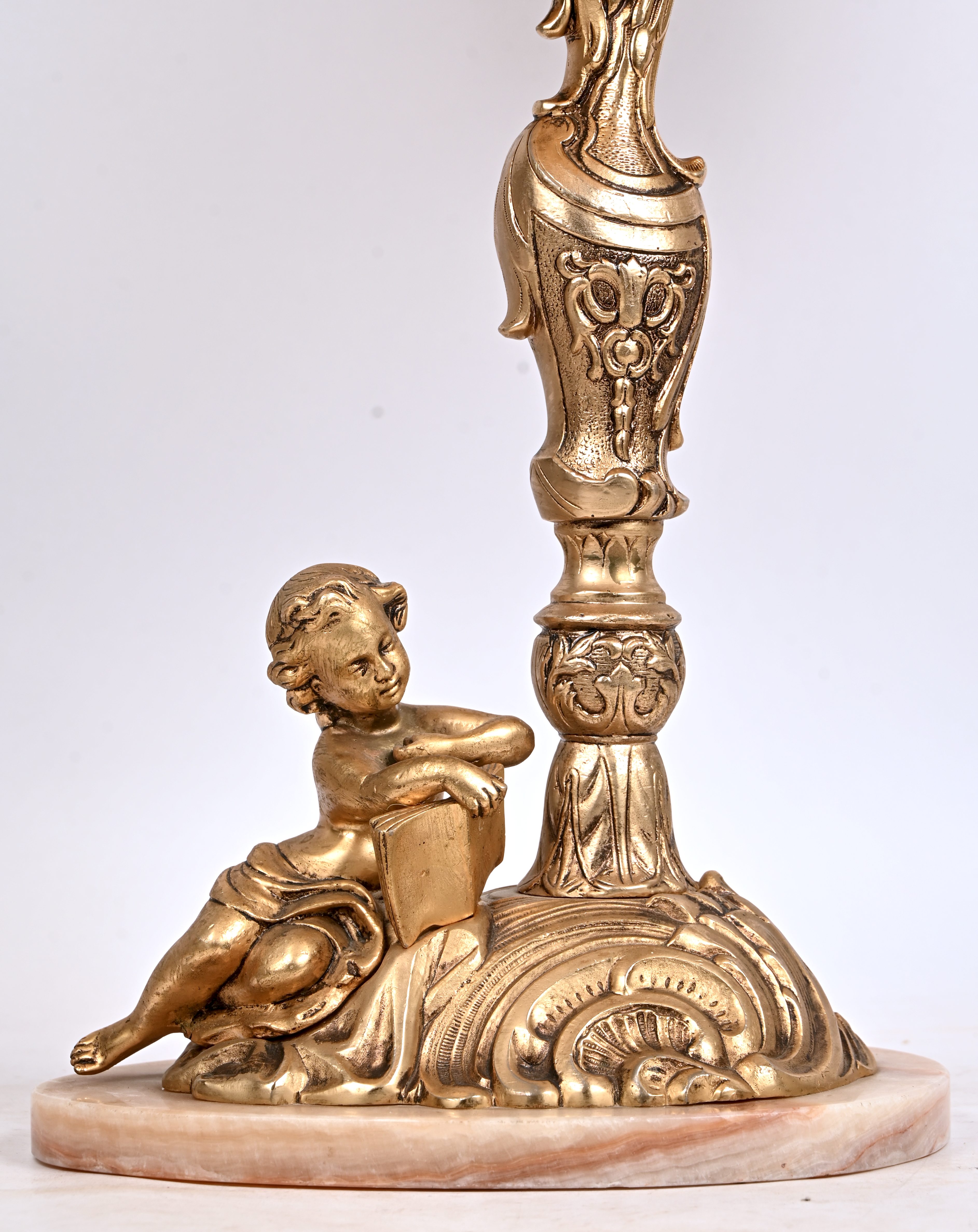 Een messing tafellamp met lezende putti op de voet Een messing tafellamp met lezende putti op de voet.