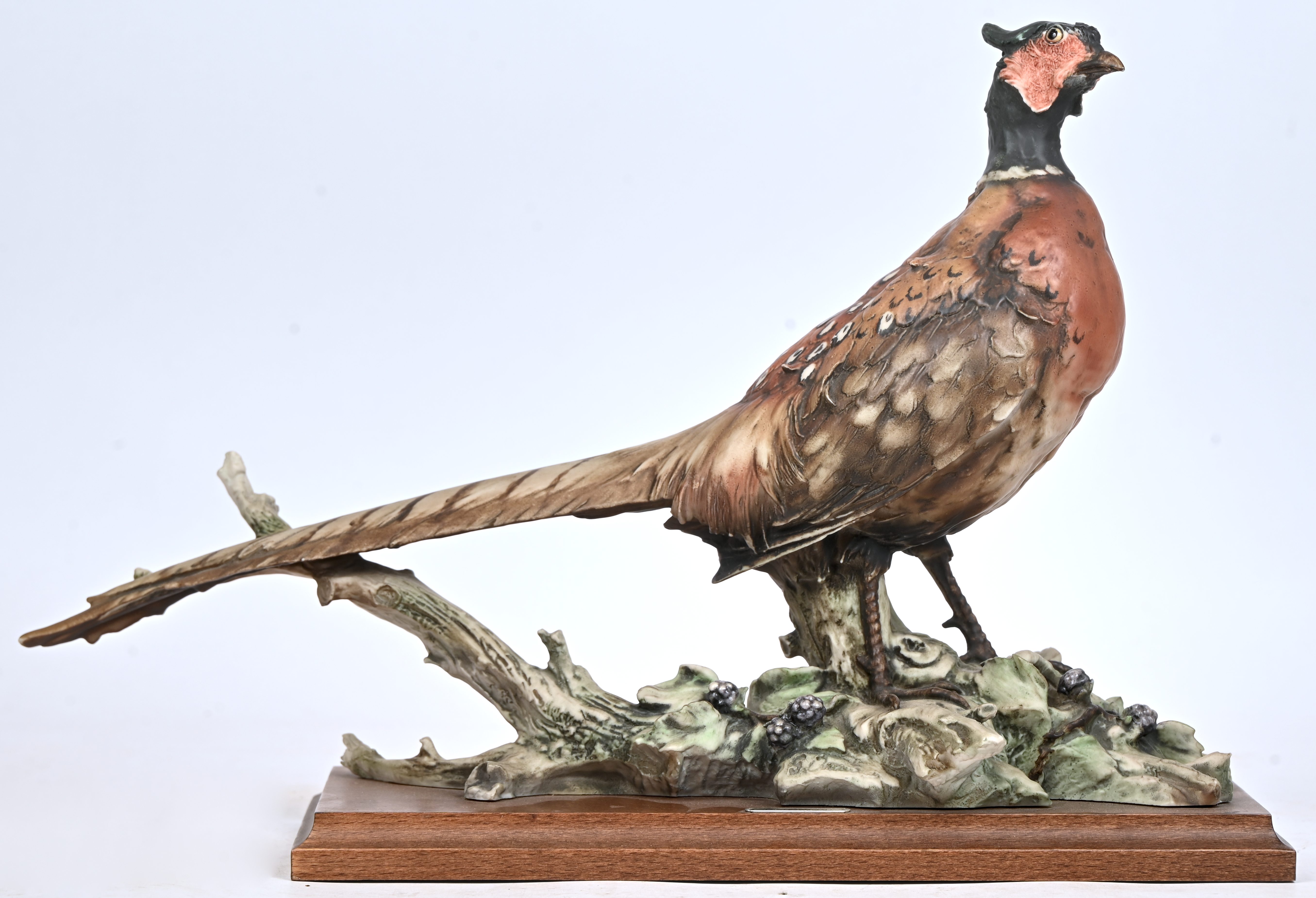 Een gegoten kunsthars beeld van een fazant, gemerkt G. Armani, Capodimonte. Op houten sokkel Een gegoten kunsthars beeld van een fazant, gemerkt G. Armani, Capodimonte. Op houten sokkel.