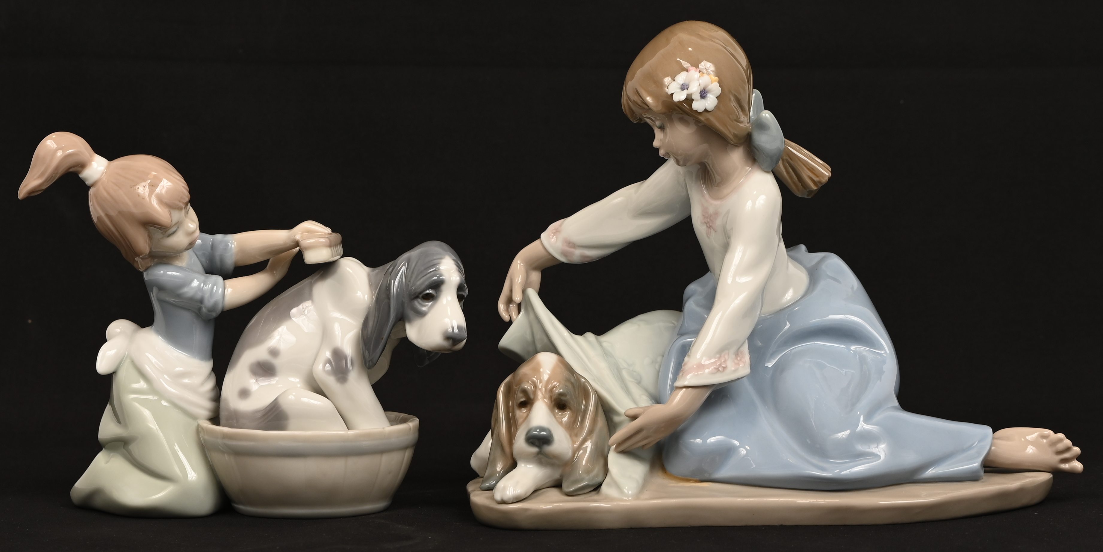 Twee porseleinen beeldjes van een meisje met hond, gemerkt Lladro Twee porseleinen beeldjes van een meisje met hond, gemerkt Lladro.