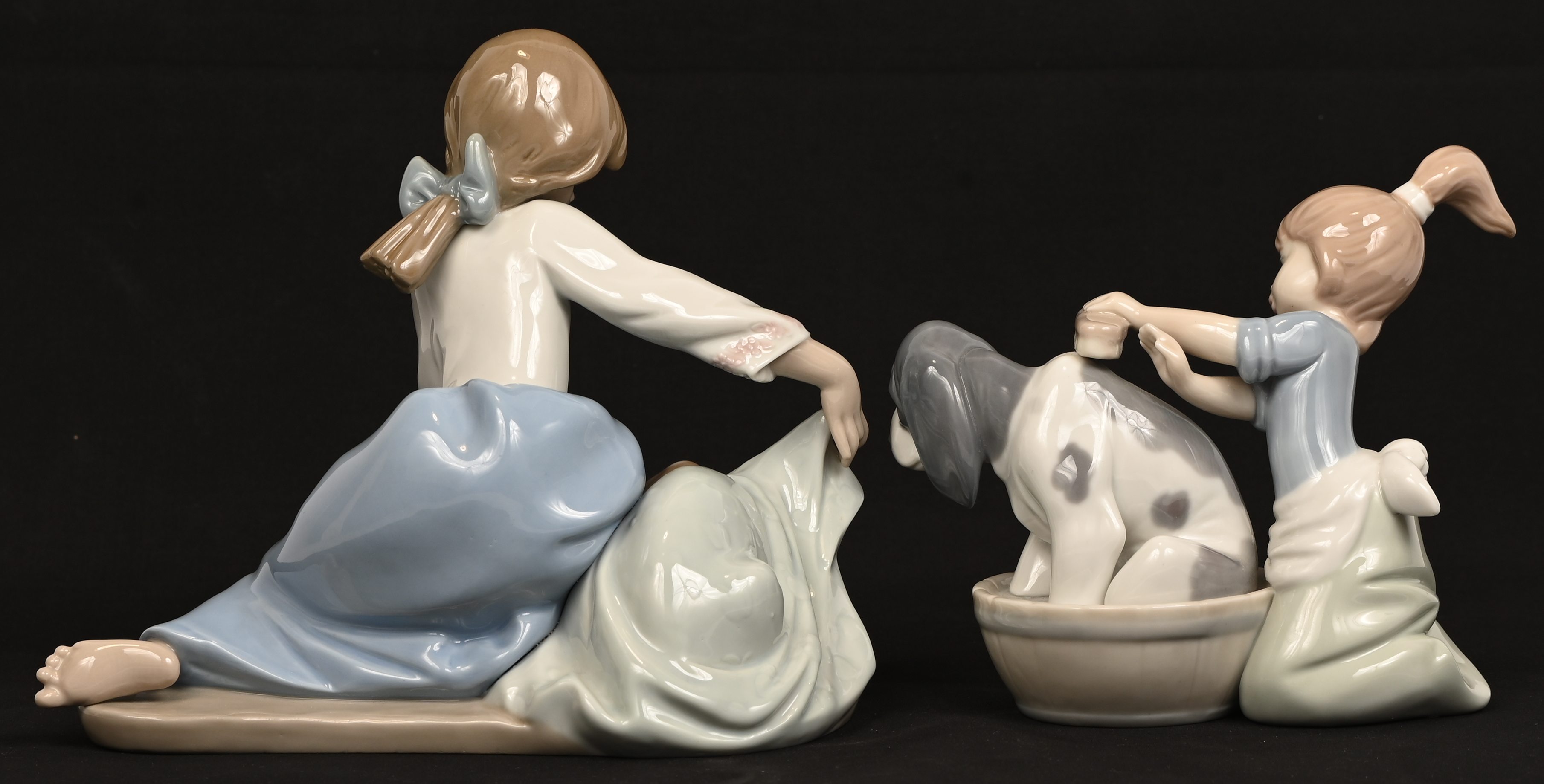 Twee porseleinen beeldjes van een meisje met hond, gemerkt Lladro Twee porseleinen beeldjes van een meisje met hond, gemerkt Lladro.