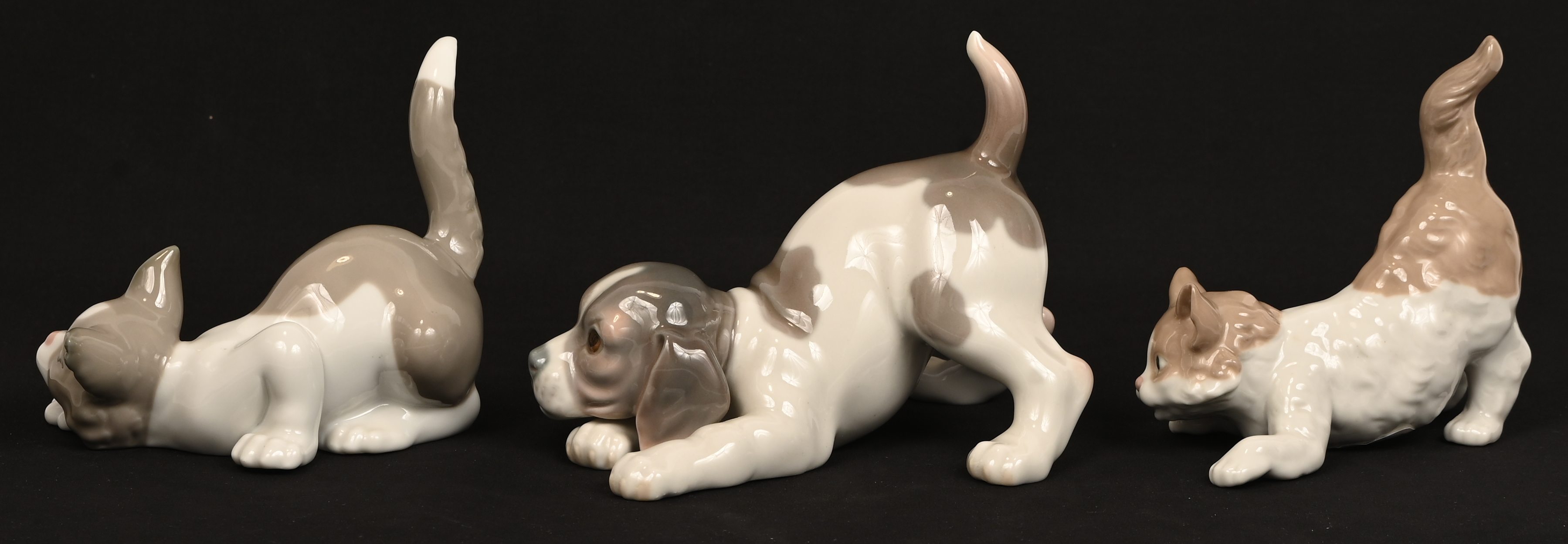 Drie porseleinen beeldjes, twee poezen en een hond, gemerkt Lladro Drie porseleinen beeldjes, twee poezen en een hond, gemerkt Lladro.