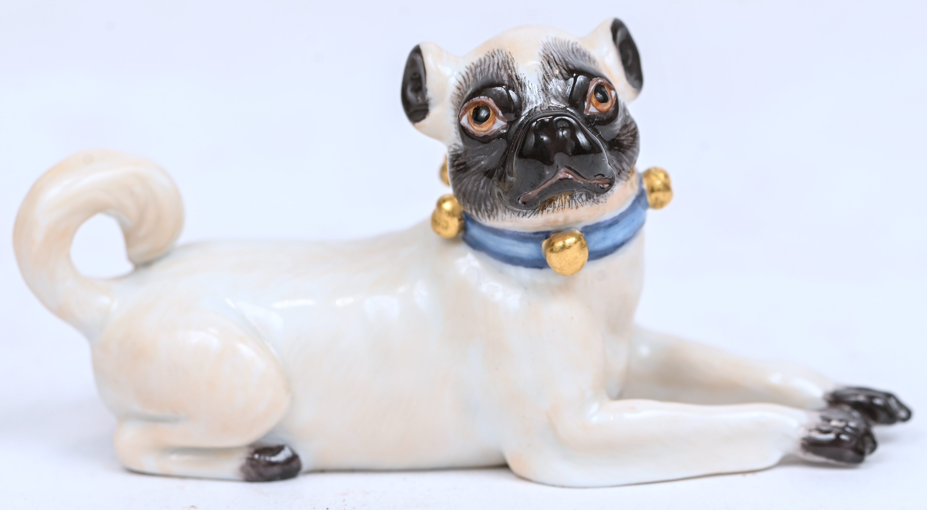 Een porseleinen miniatuurtje, liggende mopshond, gemerkt en genummerd Een porseleinen miniatuurtje, liggende mopshond, gemerkt en genummerd.