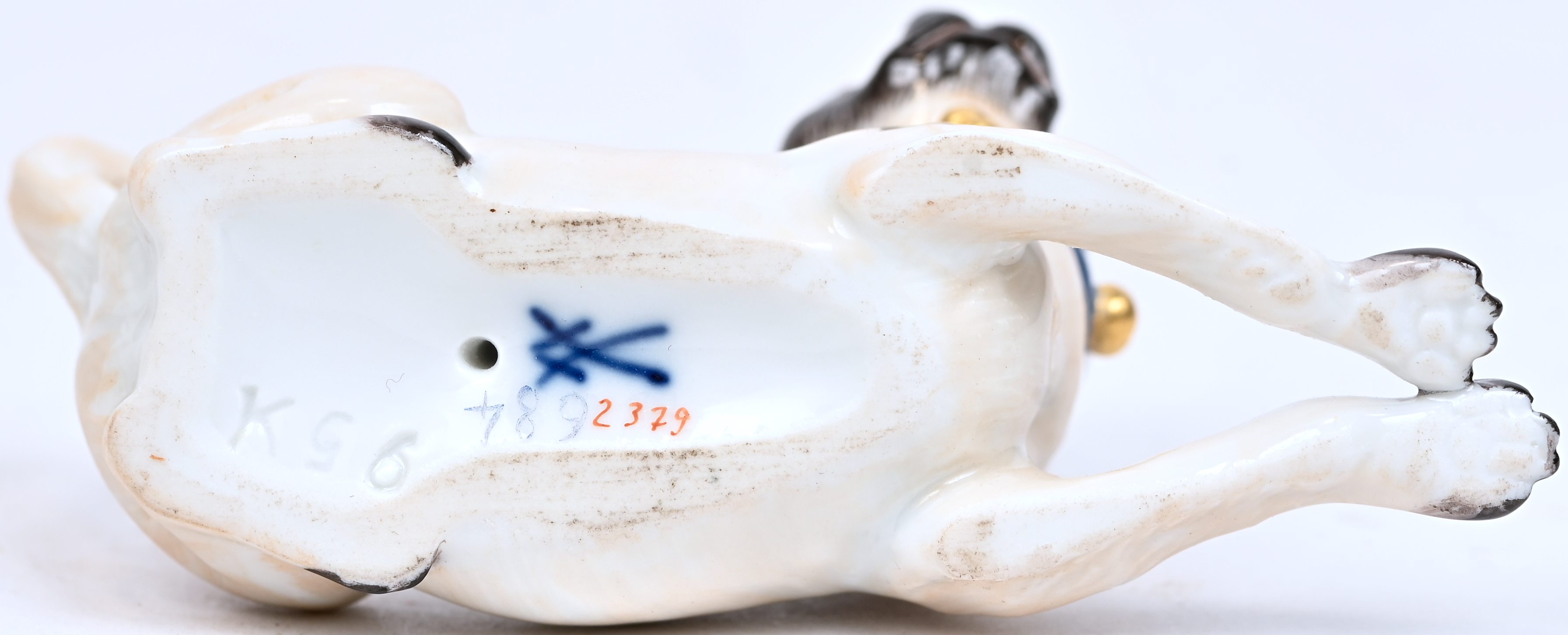 Een porseleinen miniatuurtje, liggende mopshond, gemerkt en genummerd Een porseleinen miniatuurtje, liggende mopshond, gemerkt en genummerd.