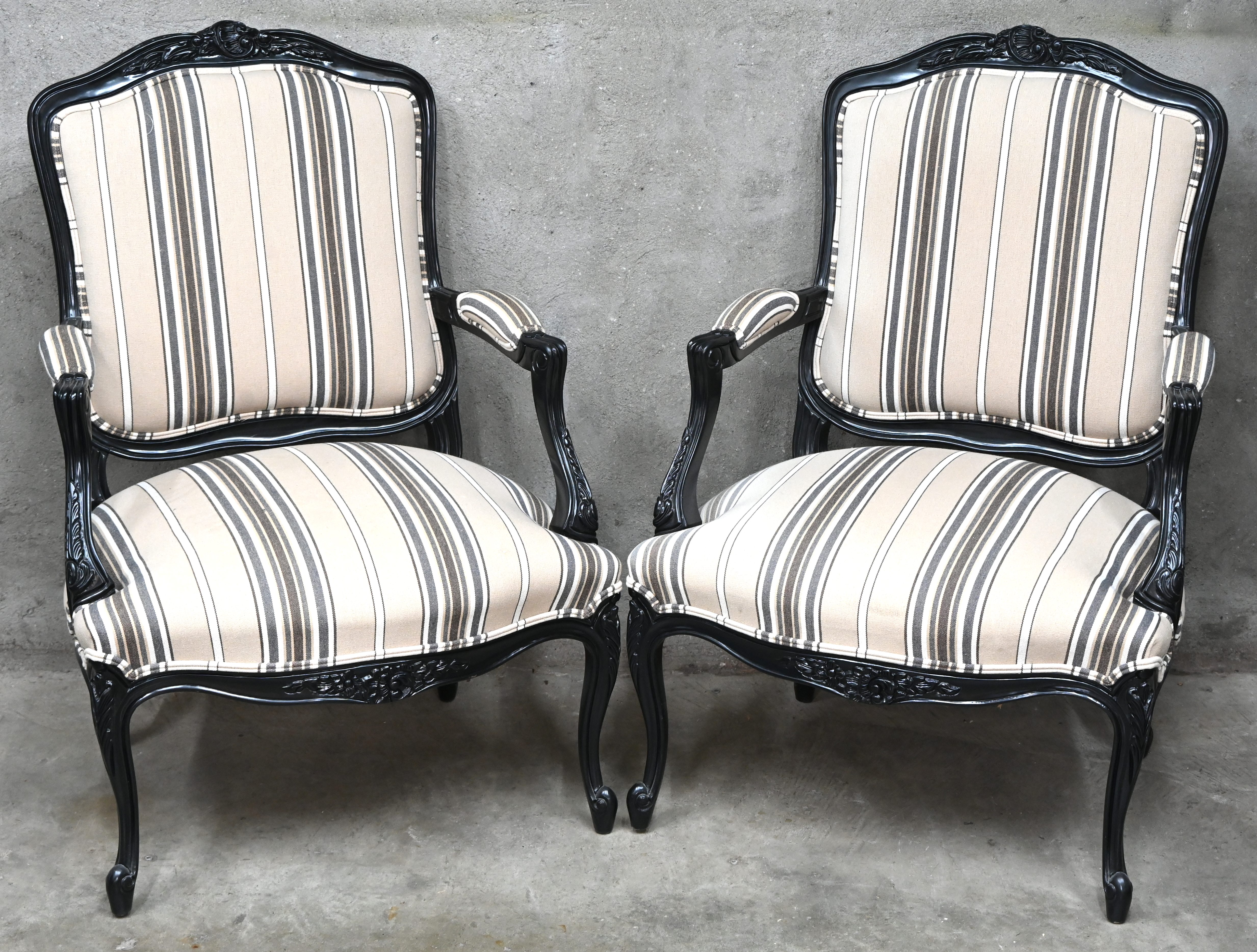 Een paar armstoelen in Louis XV stijl, zwart gelakt hout en gestreepte stoffen bekleding Een paar armstoelen in Louis XV stijl, zwart gelakt hout en gestreepte stoffen bekleding.