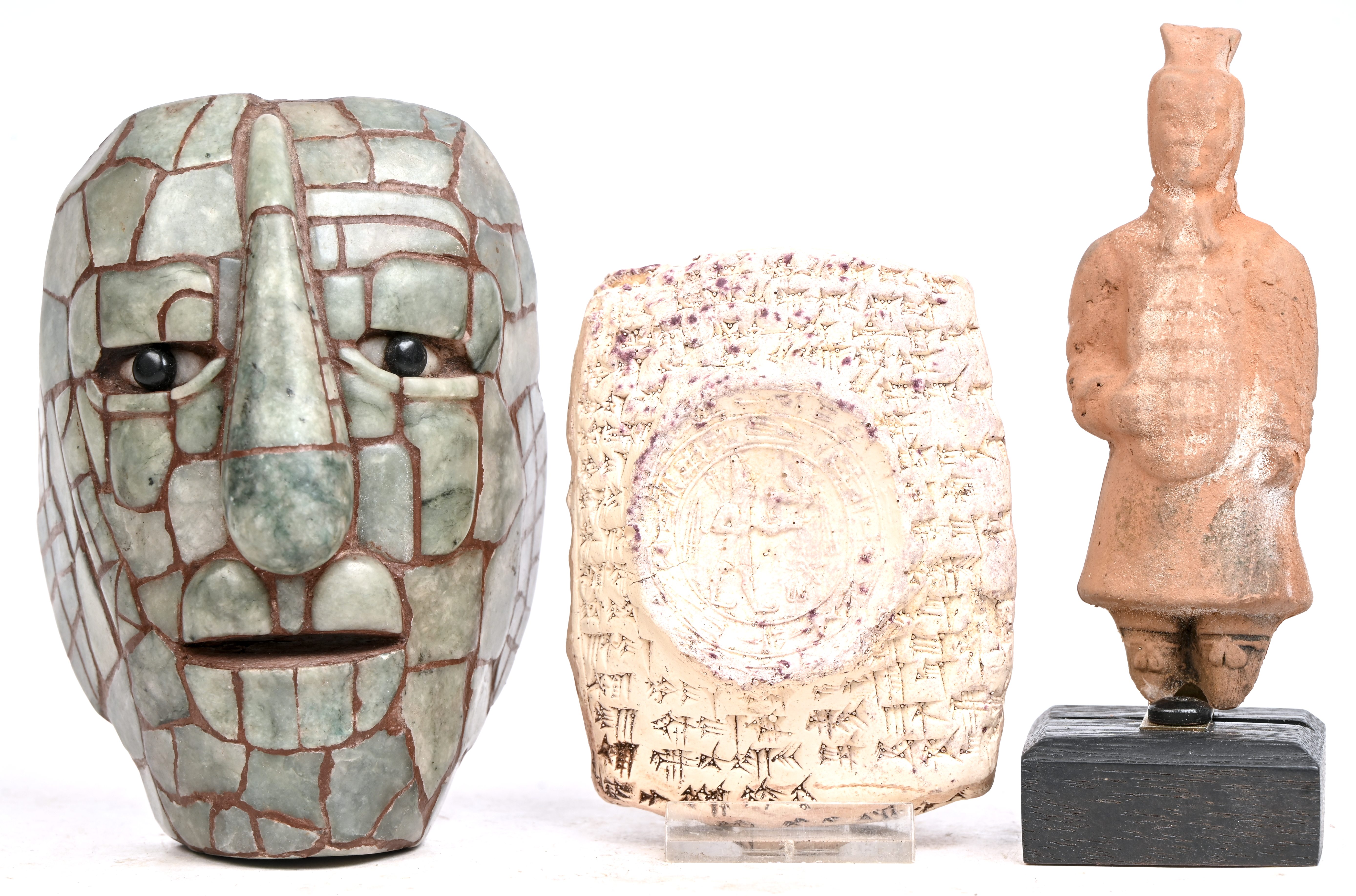 Drie voorwerpen naar de oudheid. Een terra-cotte krijgertje, een tablet met spijkerschrift en een aardewerken masker bekleed met jade Drie voorwerpen naar de oudheid. Een terra-cotte krijgertje, een tablet met spijkerschrift en een aardewerken masker bekleed met jade.