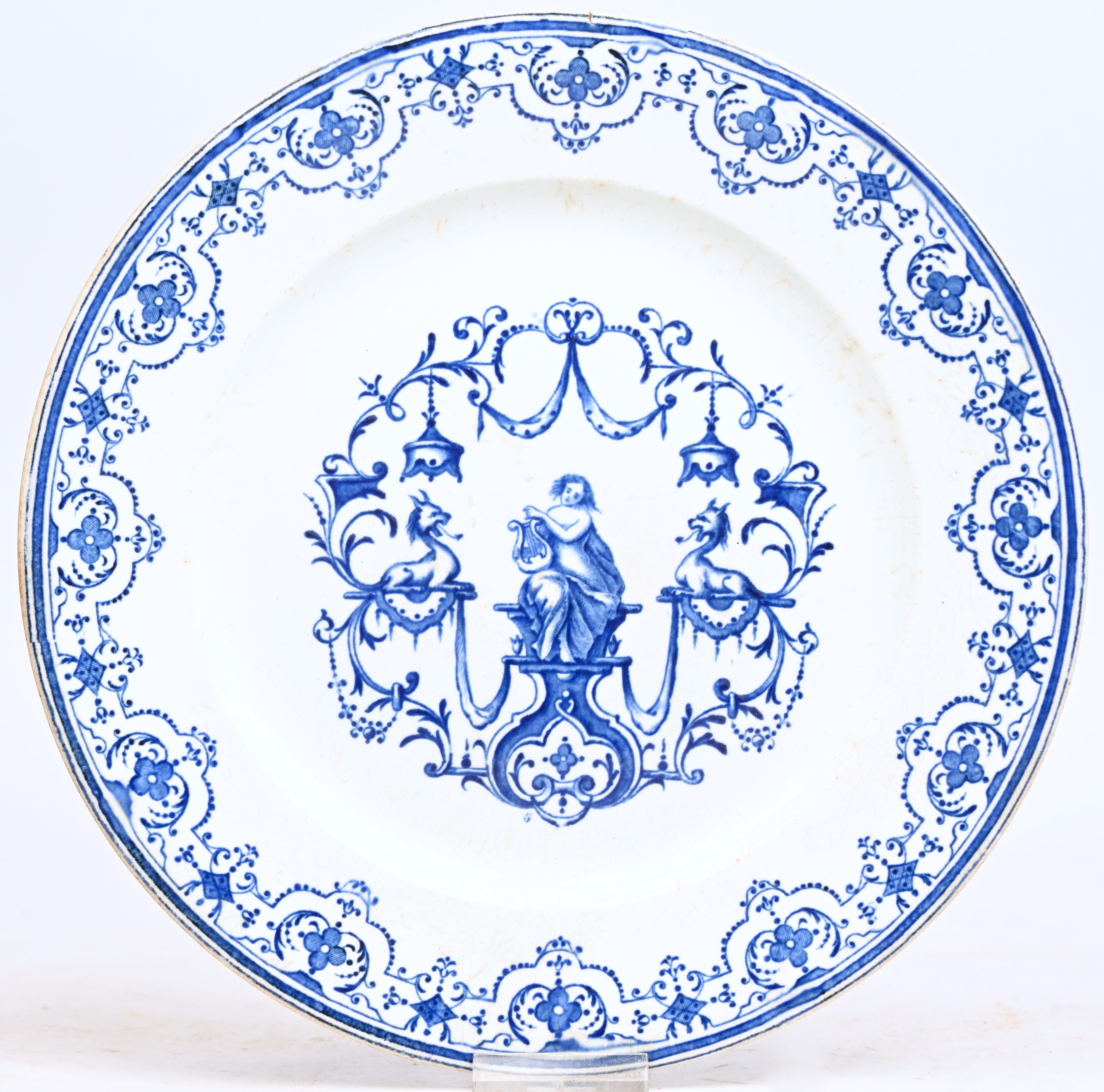 Een schotel op voet van blauw-wit geglazuurd aardewerk. Onderaan gemerkt ‘Moustiers’. Minieme schade Een schotel op voet van blauw-wit geglazuurd aardewerk. Onderaan gemerkt ‘Moustiers’. Minieme schade.
