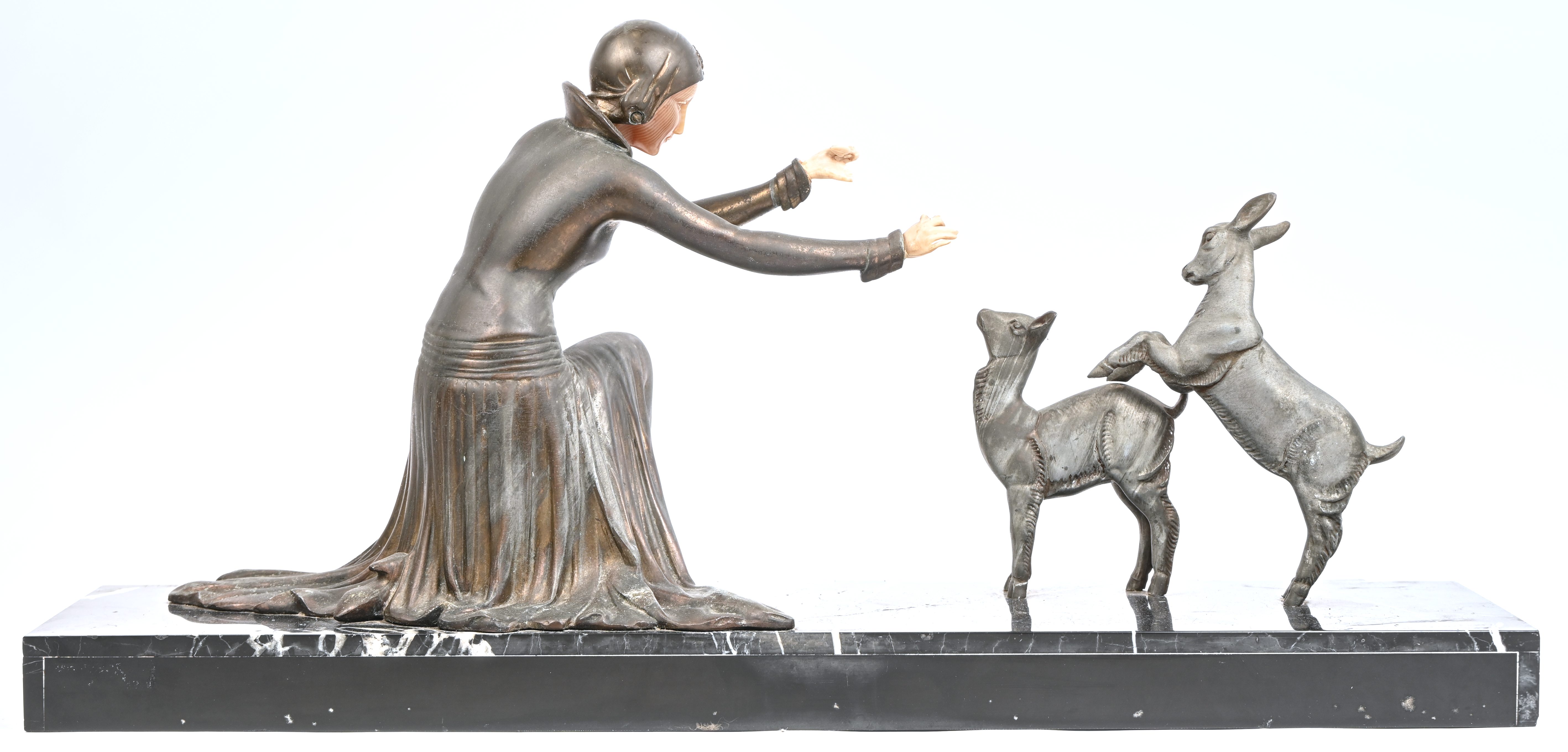 ‘Jonge vrouw met twee geitjes’, een art-deco beeld van gepatineerd zamac en kunsthars. Gesigneerd op de marmeren voet. Van het linkerhand zijn enkele vingers manco ‘Jonge vrouw met twee geitjes’, een art-deco beeld van gepatineerd zamac en kunsthars. Gesigneerd op de marmeren voet. Van het linkerhand zijn enkele vingers manco.