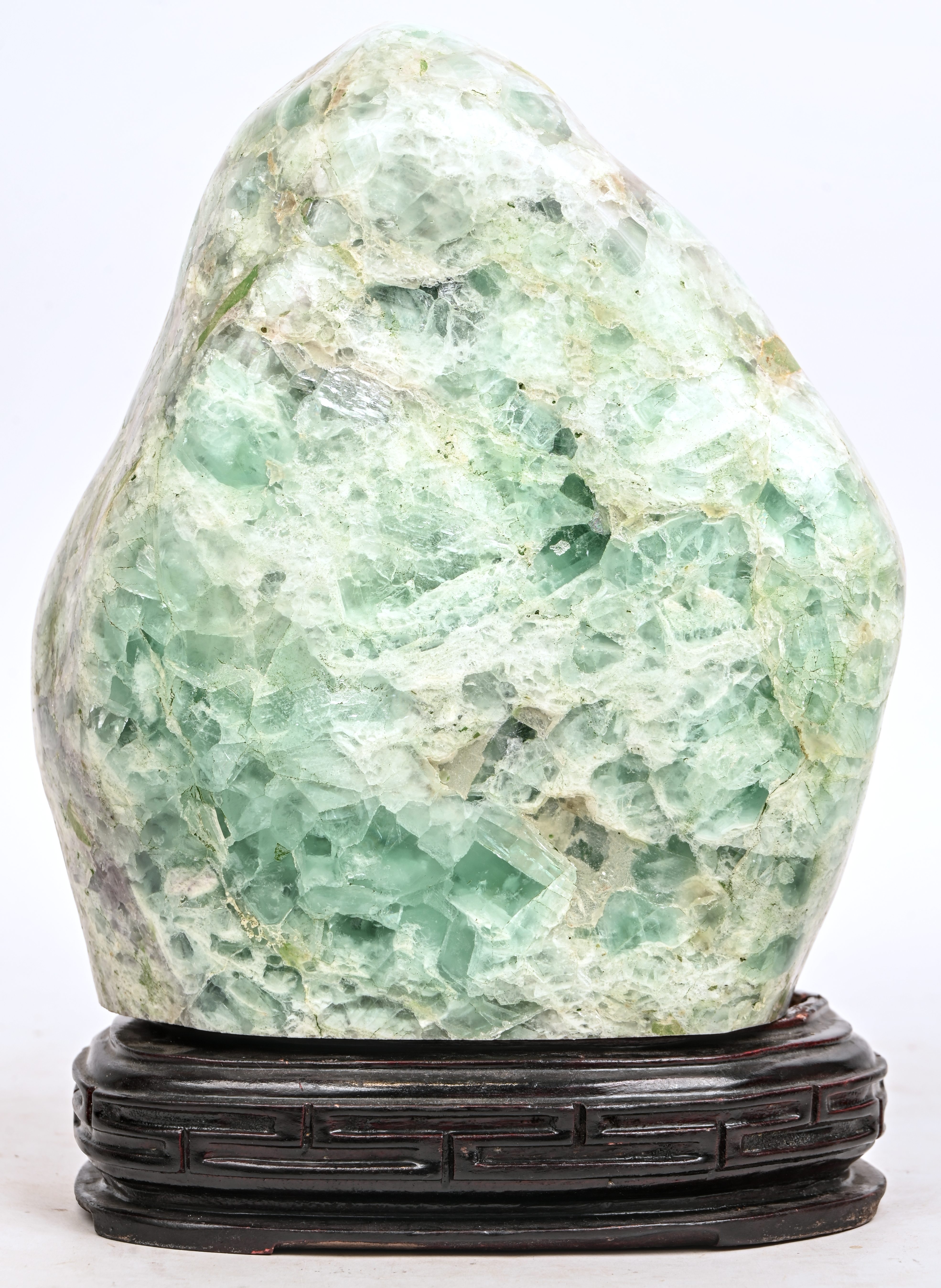 Een groot stuk jade op houten sokkel Een groot stuk jade op houten sokkel.
