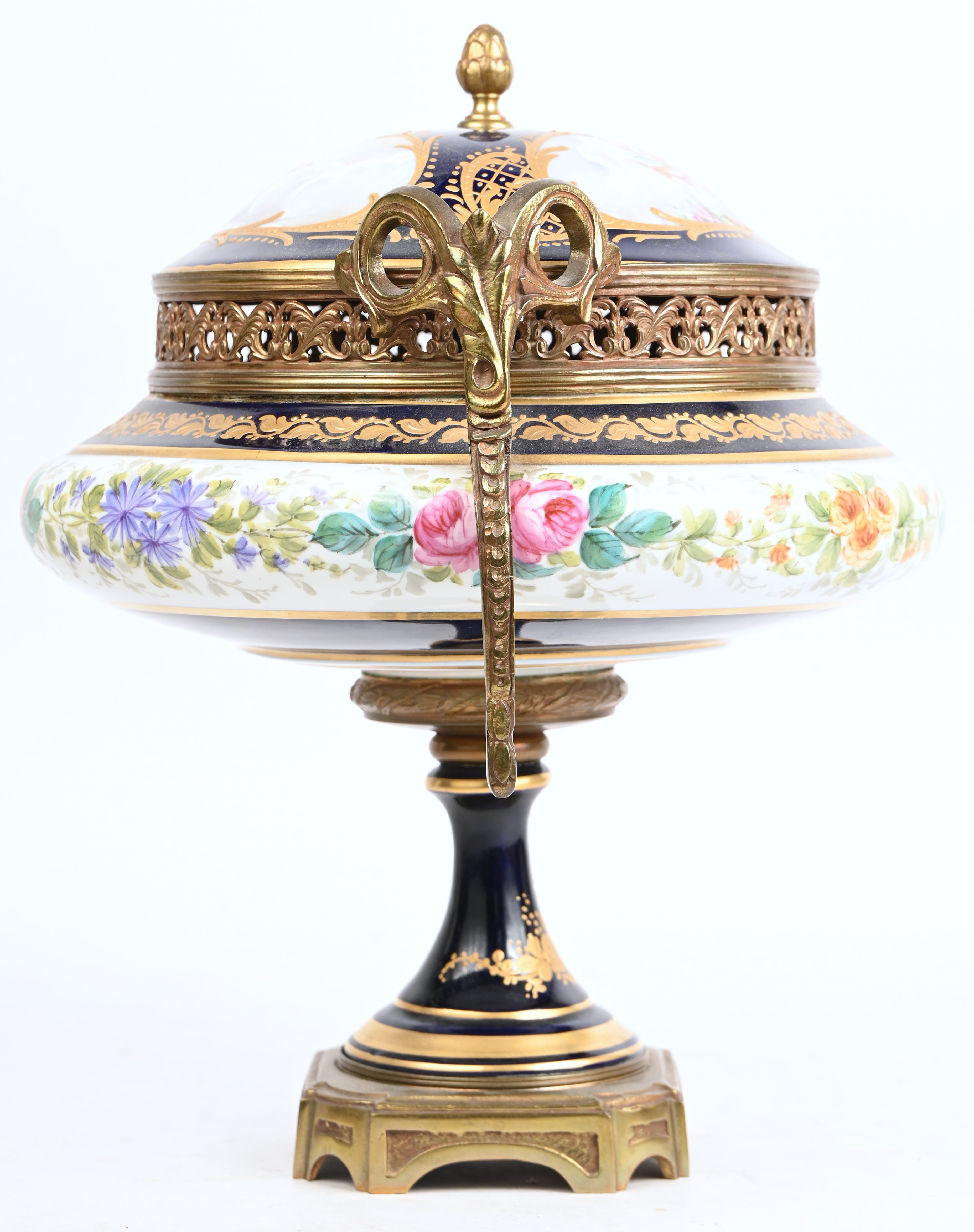Een porseleinen coupe met deksel op voet met een decor van engelen en bloemen, gemerkt Sèvres en gesigneerd E. Froger Een porseleinen coupe met deksel op voet met een decor van engelen en bloemen, gemerkt Sèvres en gesigneerd E. Froger.