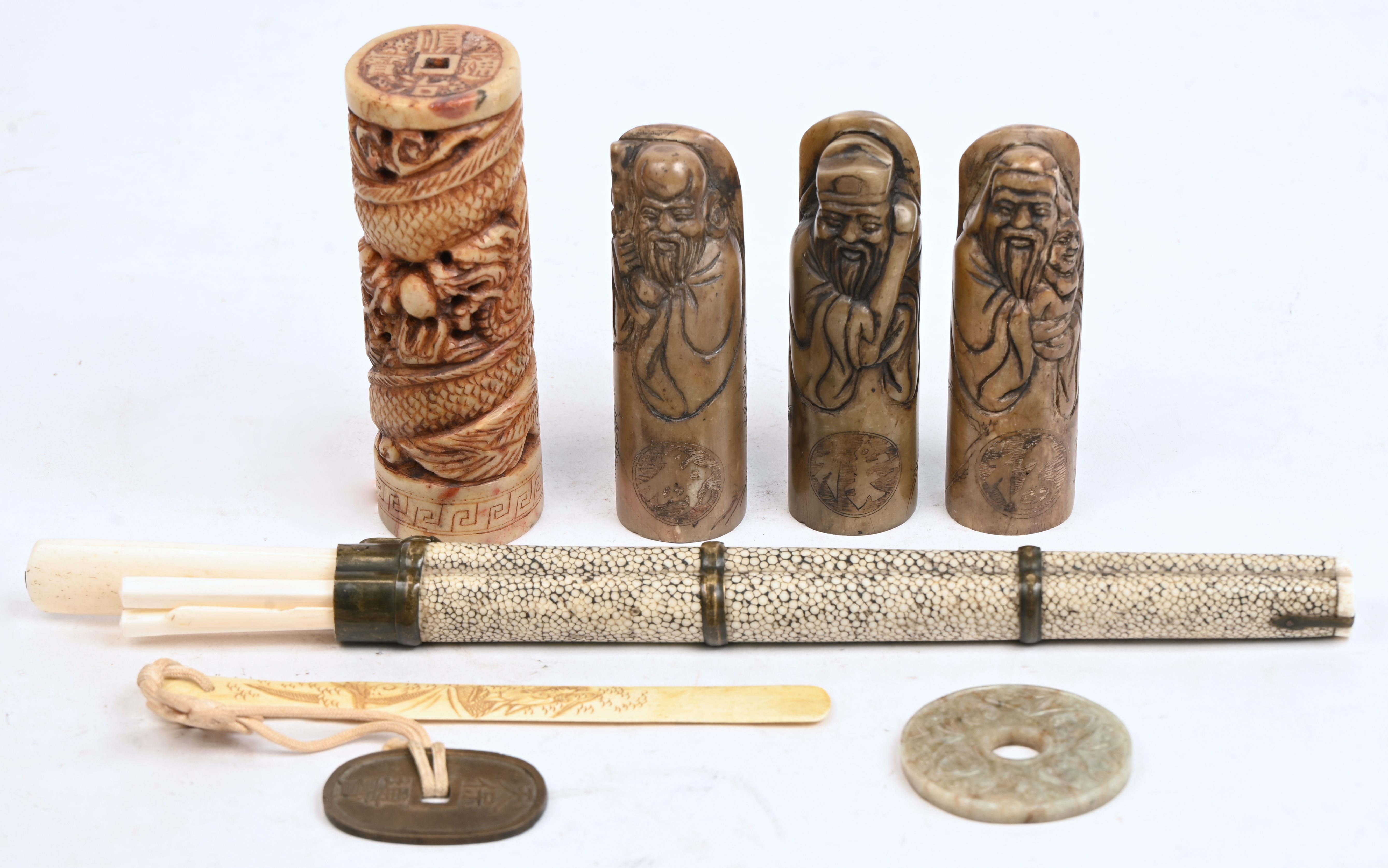 Een lot Chinese voorwerpen bestaande uit 4 spekstenen stempels, een benen briefopener, een benen set met chopsticks en mes in houder en een jade bi-schijf Een lot Chinese voorwerpen bestaande uit 4 spekstenen stempels, een benen briefopener, een benen set met chopsticks en mes in houder en een jade bi-schijf.