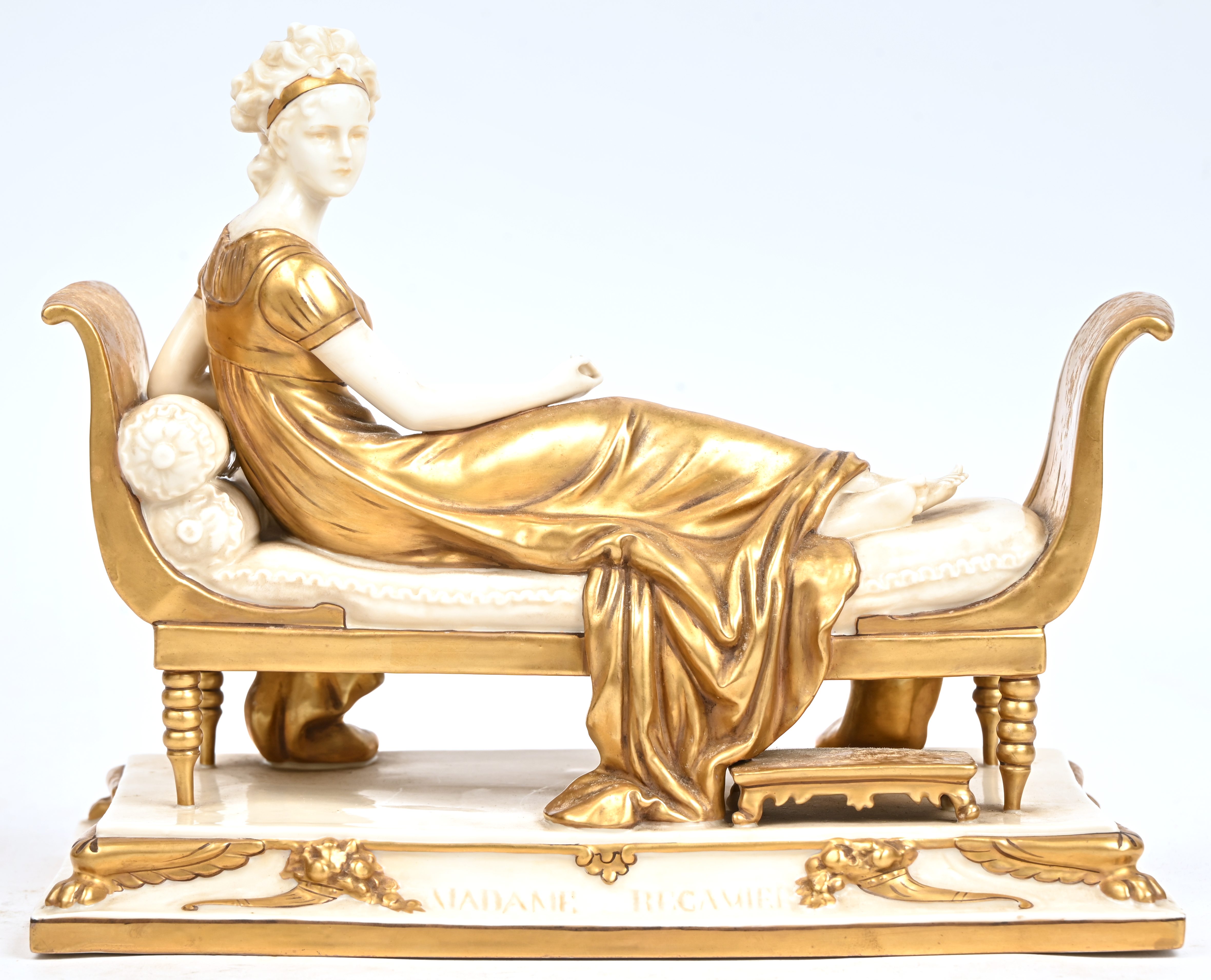 ‘Madame de Recamier’, een beeld van wit porselein met goudkleurige delen. Gemerkt en genummerd ‘9447-27’ ‘Madame de Recamier’, een beeld van wit porselein met goudkleurige delen. Gemerkt en genummerd ‘9447-27’.