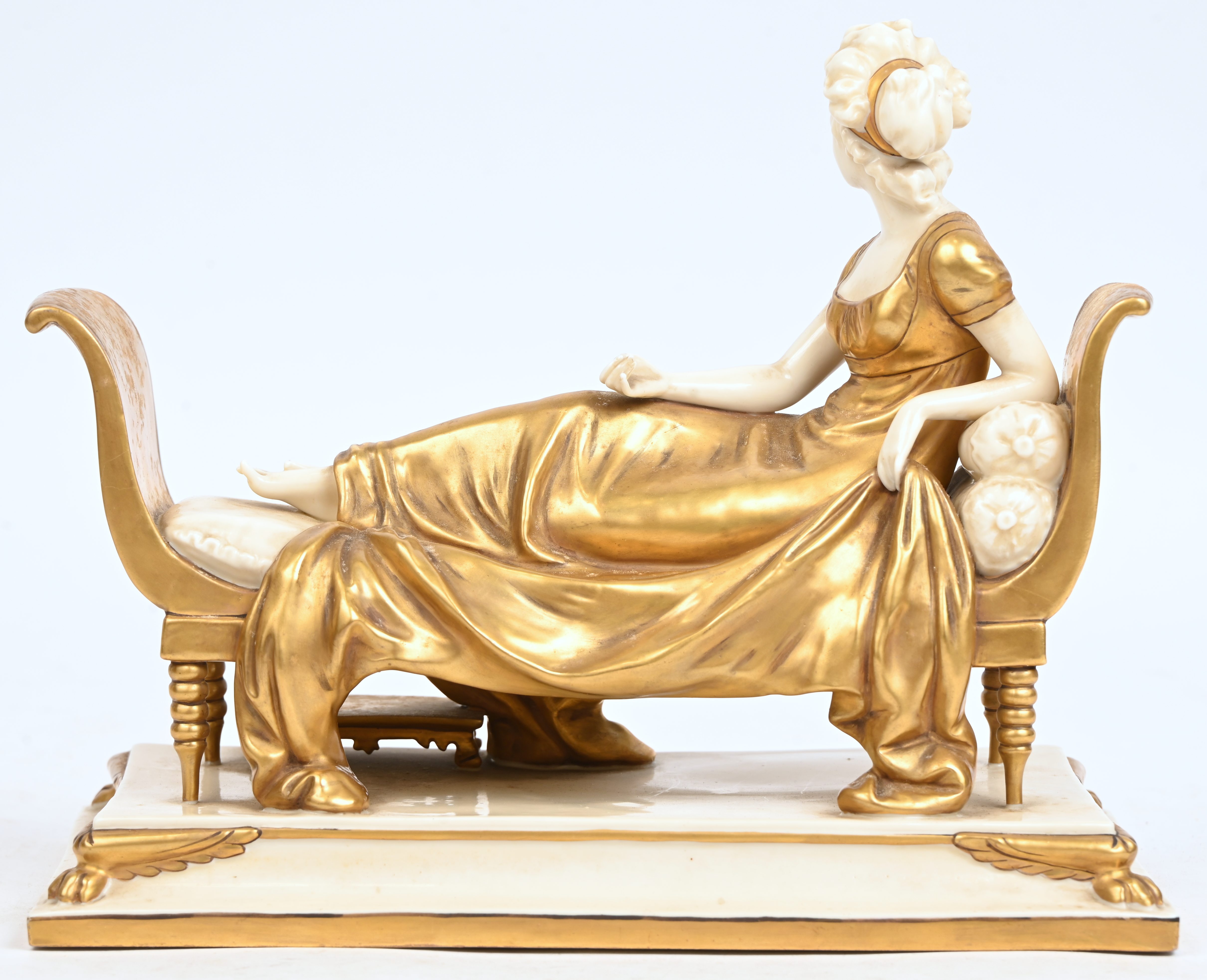 ‘Madame de Recamier’, een beeld van wit porselein met goudkleurige delen. Gemerkt en genummerd ‘9447-27’ ‘Madame de Recamier’, een beeld van wit porselein met goudkleurige delen. Gemerkt en genummerd ‘9447-27’.